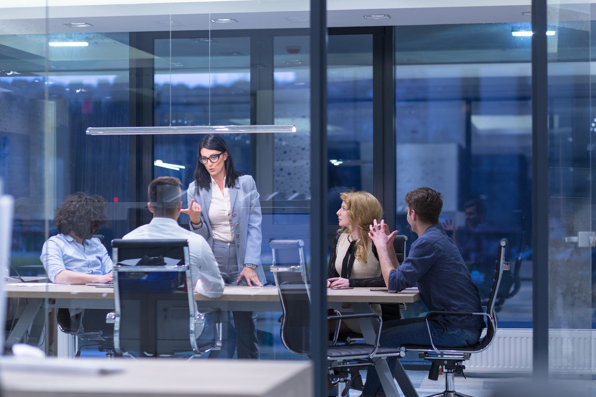 A group of people are sitting around a table in an office having a meeting.