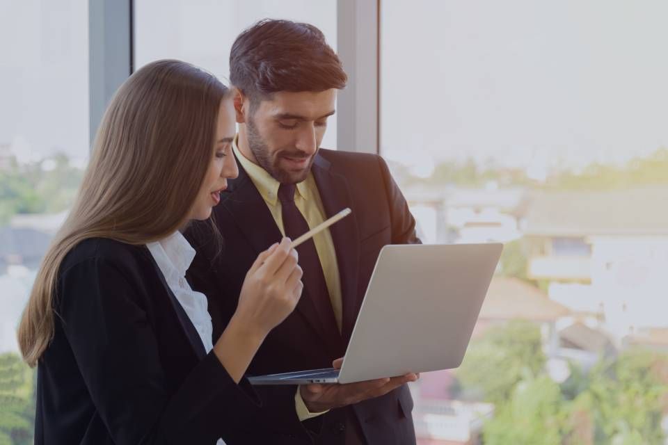 A man and a woman are looking at a laptop computer.