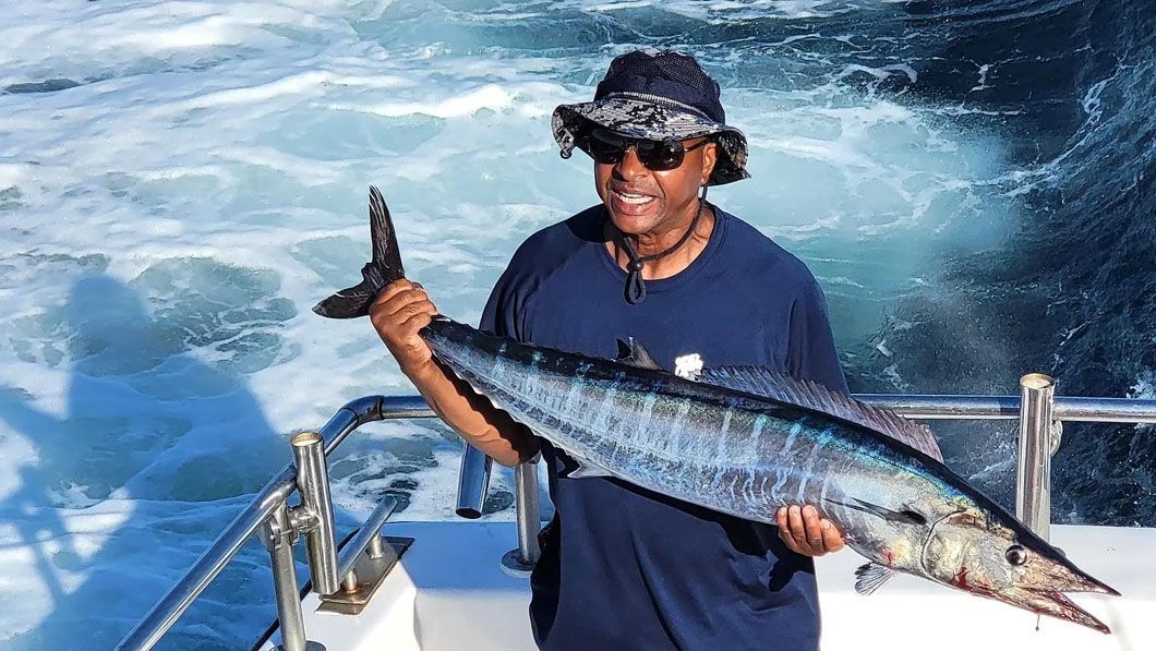 A man is holding a large fish on a boat.
