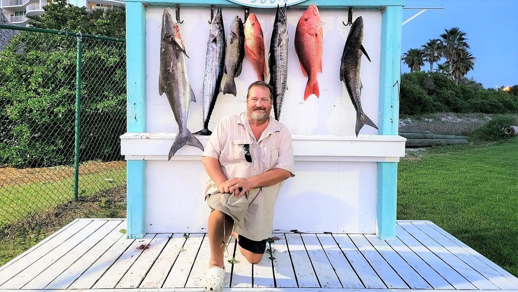 A man is sitting in front of a display of fish.