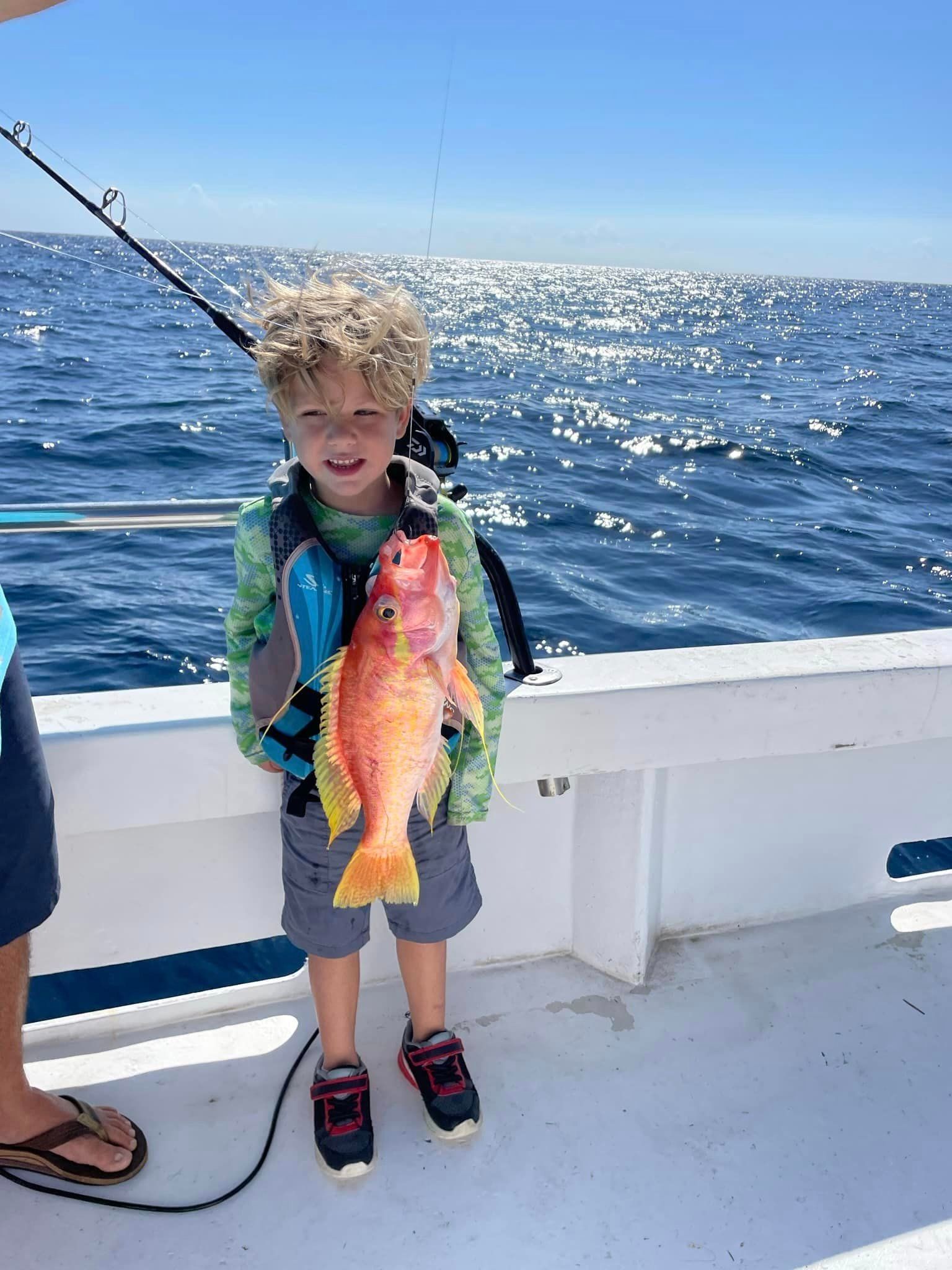 A young boy is holding a fish on a boat.