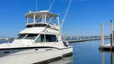 A white boat is docked at a dock in the water.