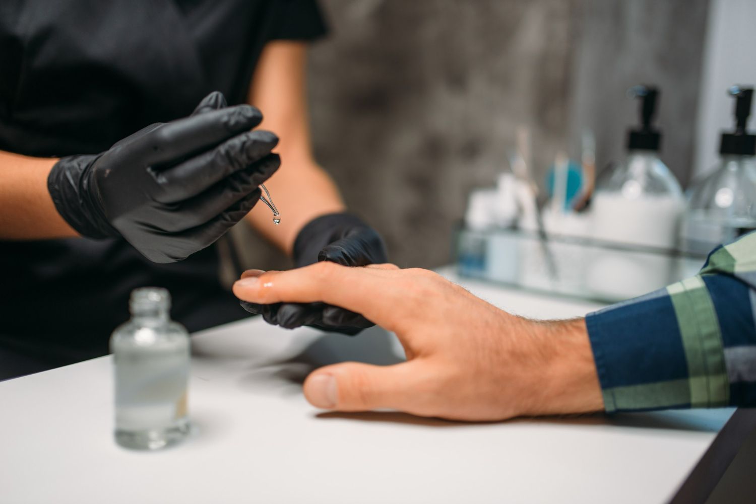 A man is getting his nails painted by a woman in a nail salon.