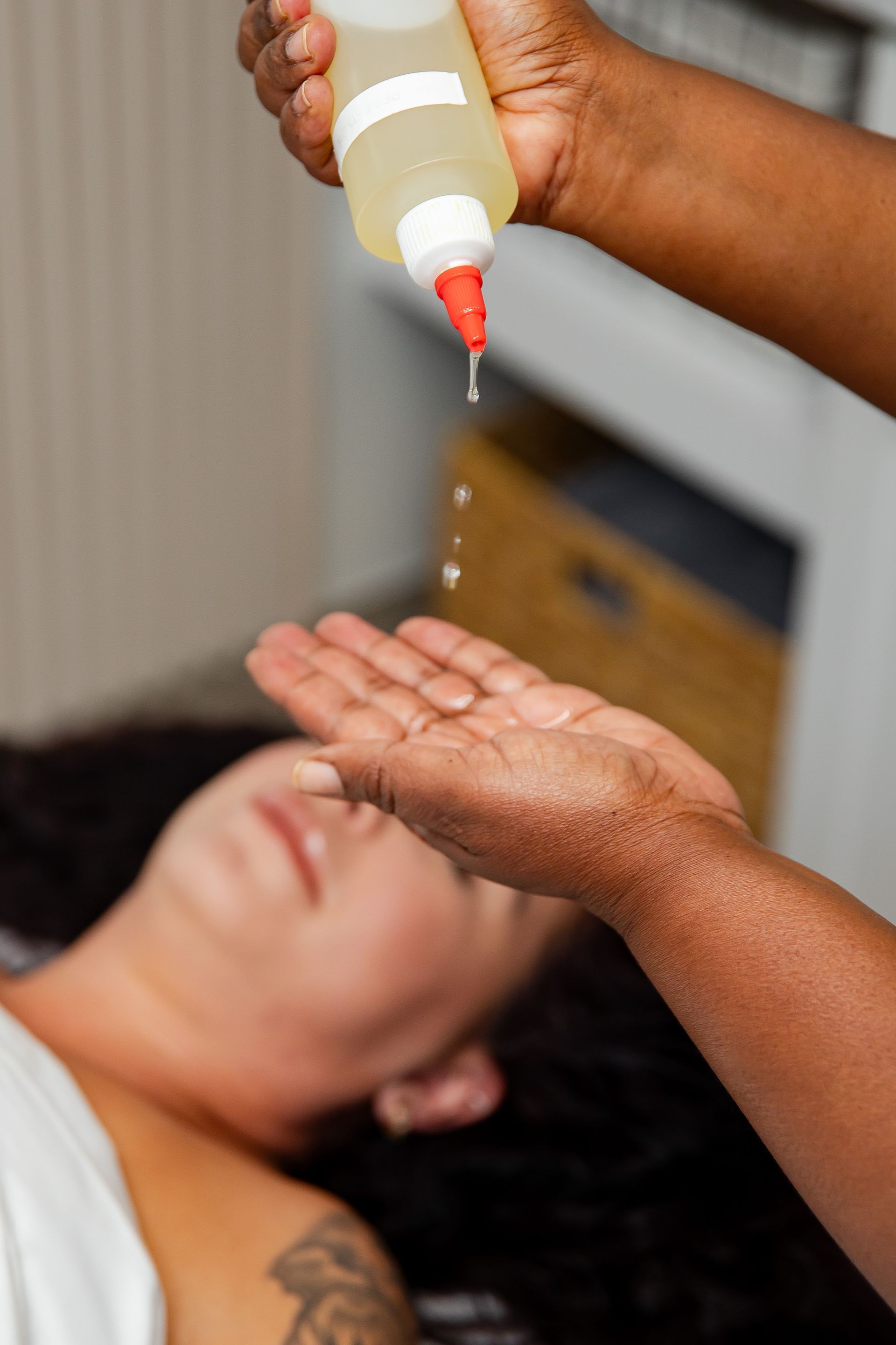 A woman is getting a massage with a bottle of oil on her hand.