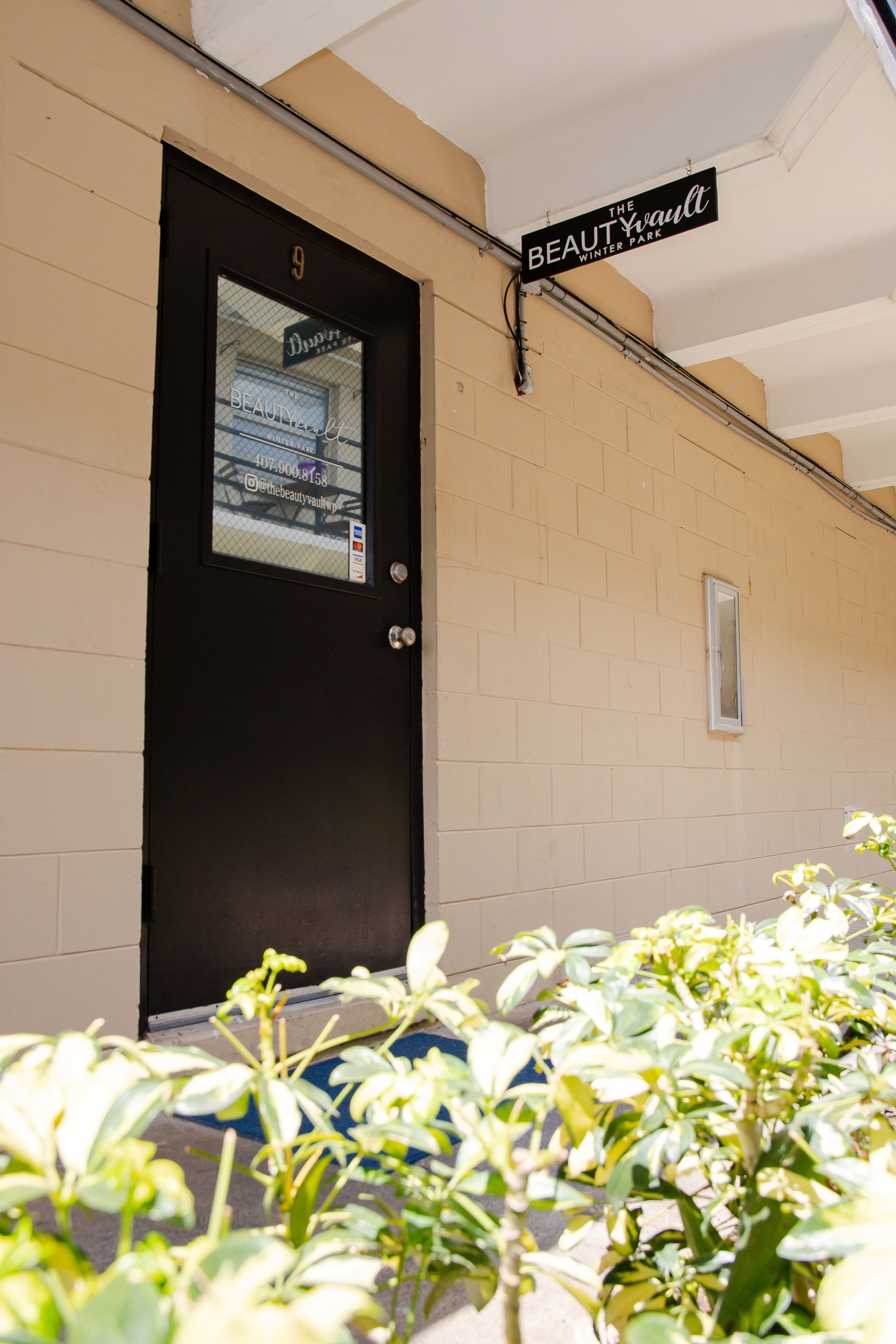 A black door with a glass window is on the side of a building.