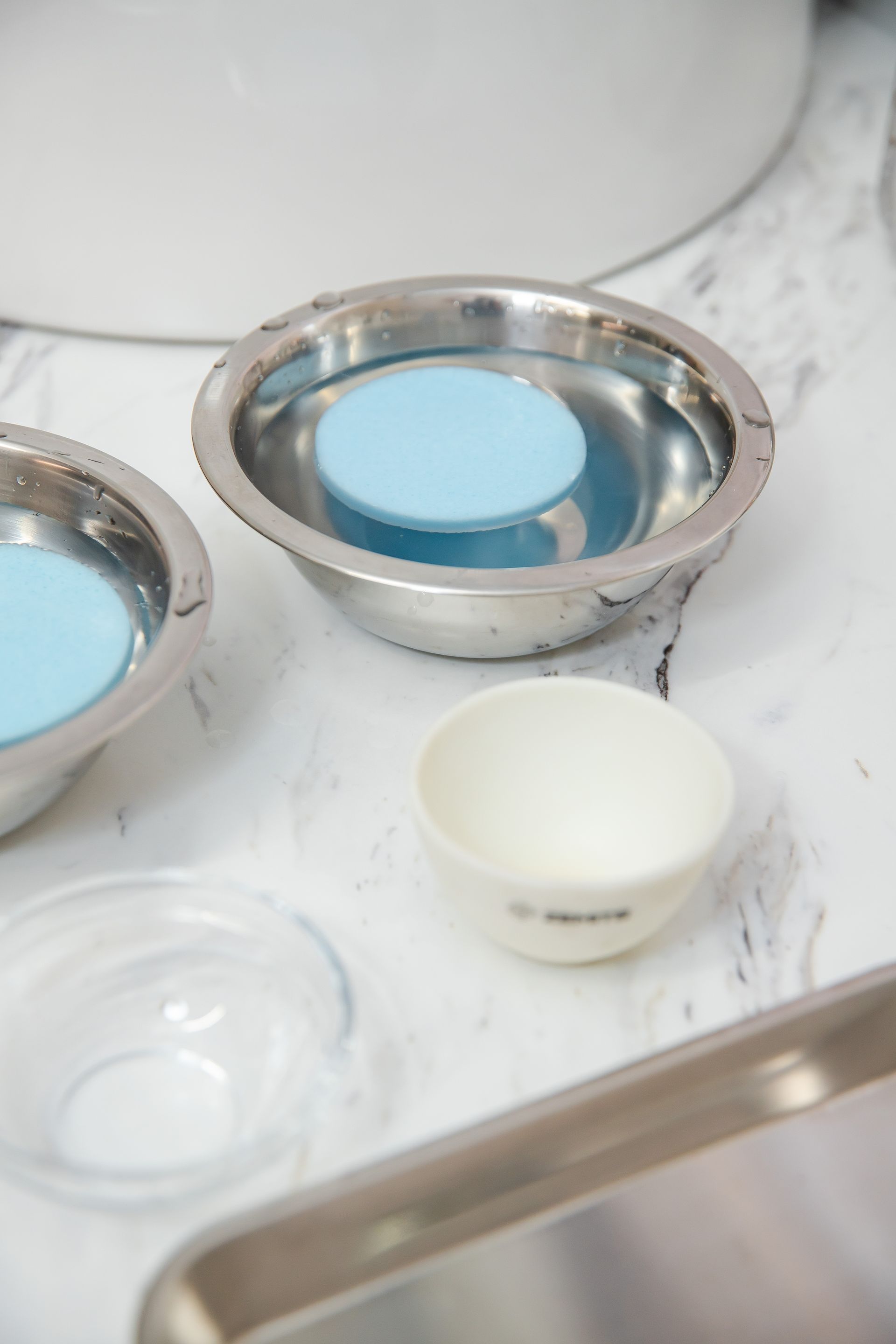 A stainless steel bowl with a blue circle in it is sitting on a counter next to a sink.