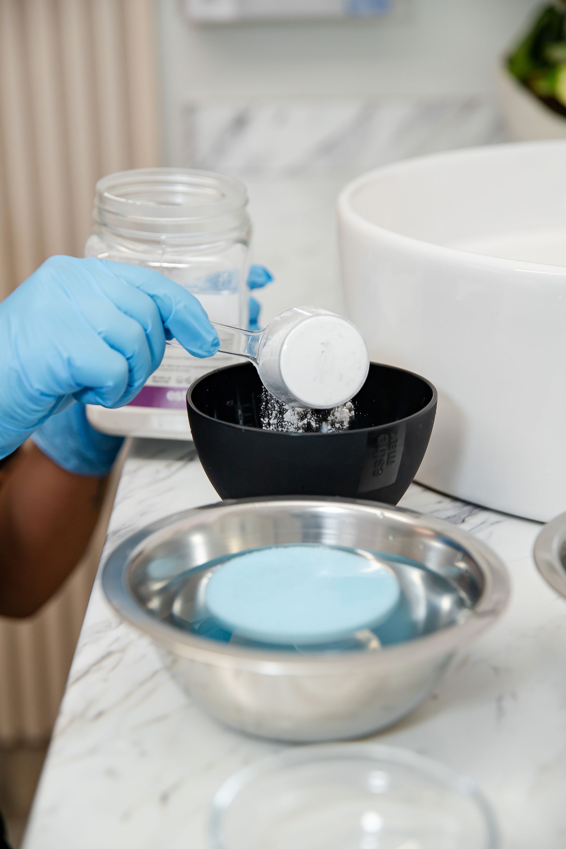 A person is pouring soap into a bowl of water.