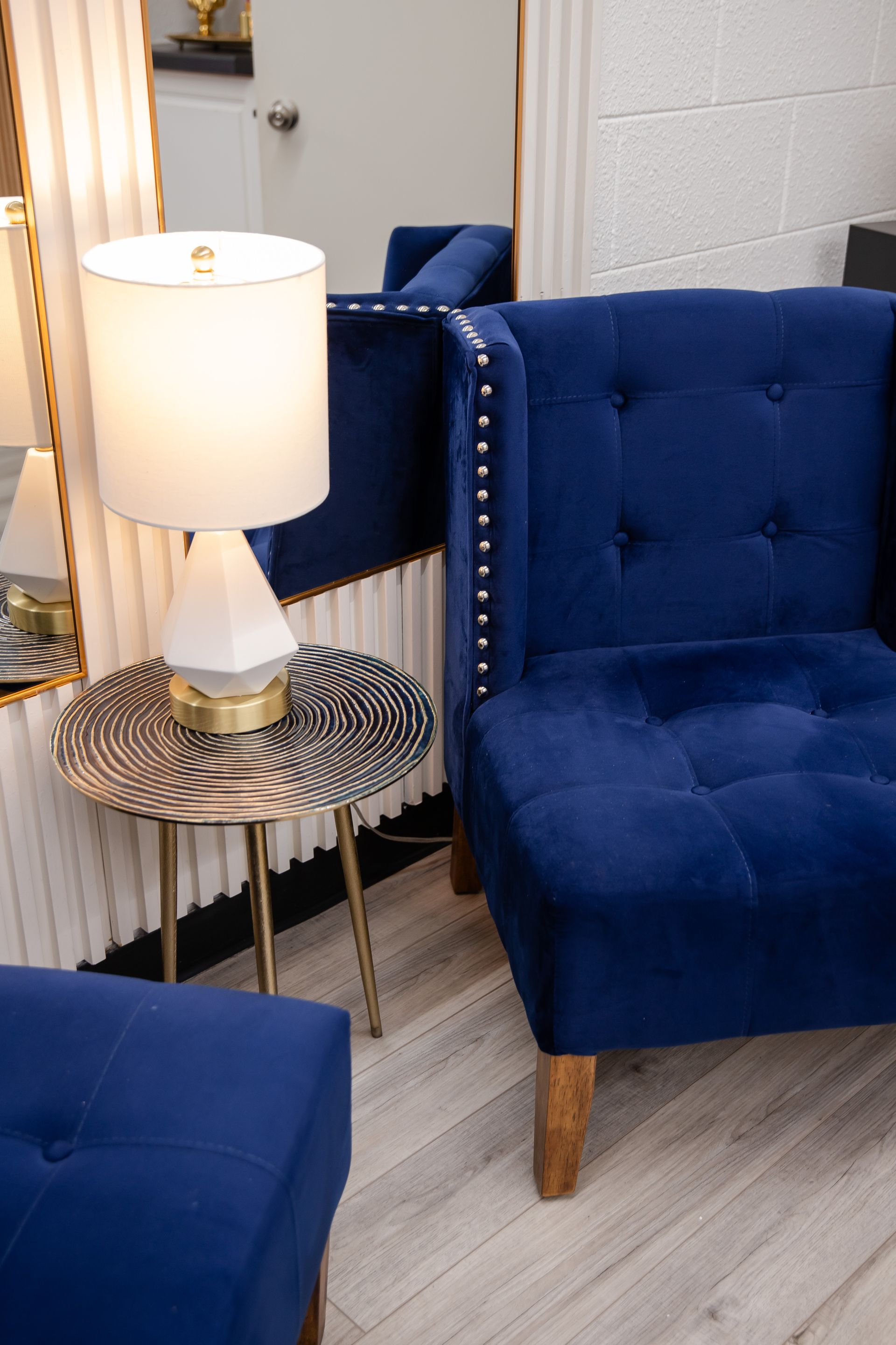 A blue chair is sitting next to a table with a lamp on it.