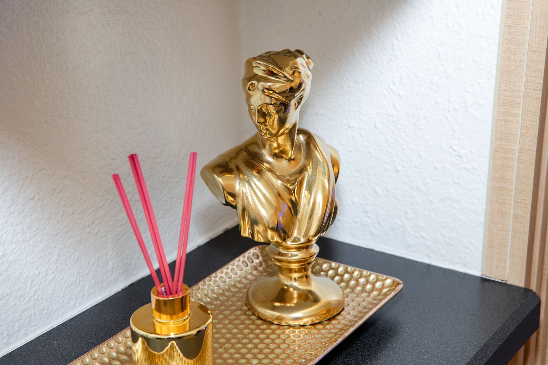 A gold statue is sitting on top of a gold tray on a table.