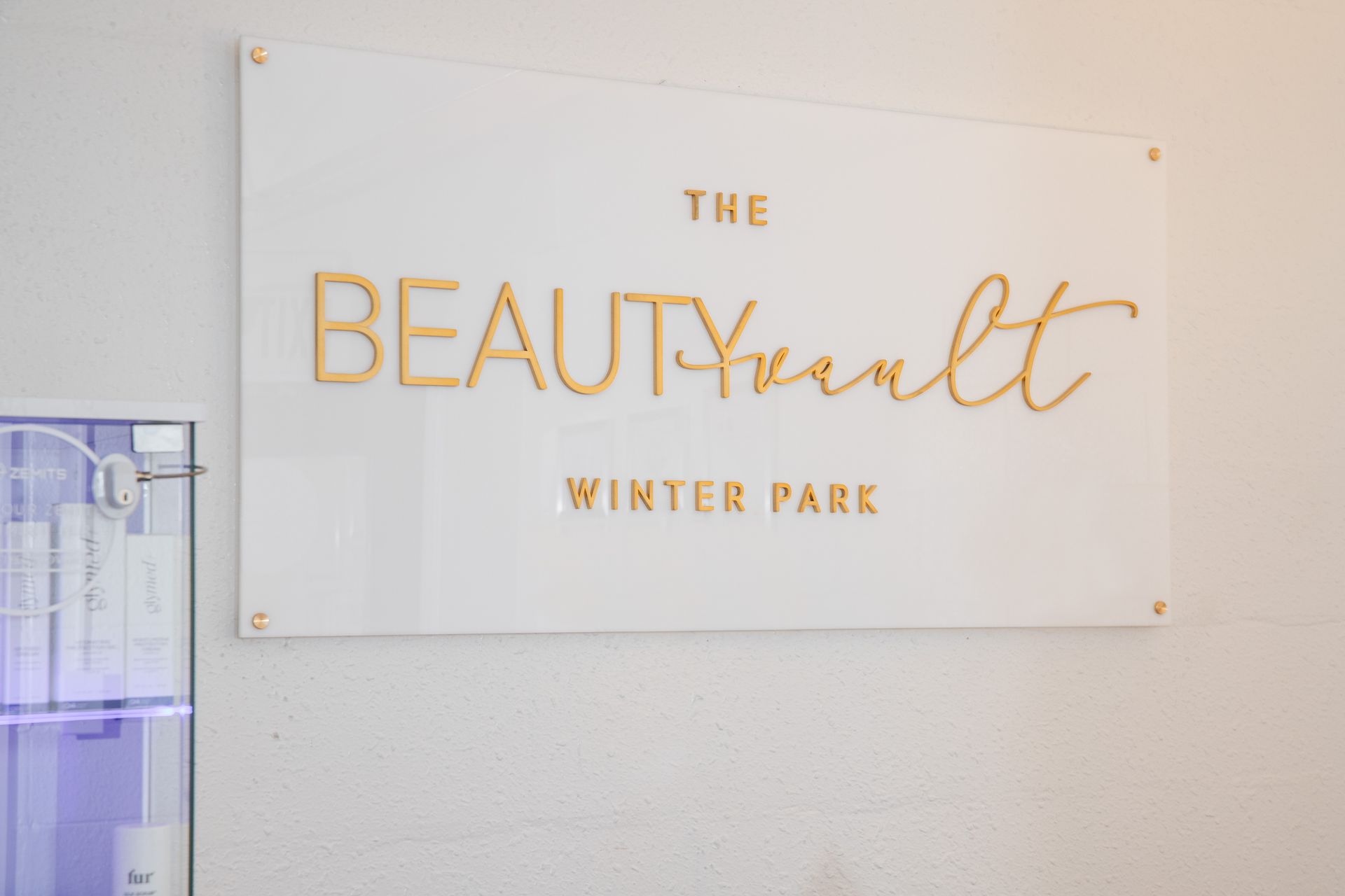 A white sign on a wall that says `` the beauty vault winter park ''.