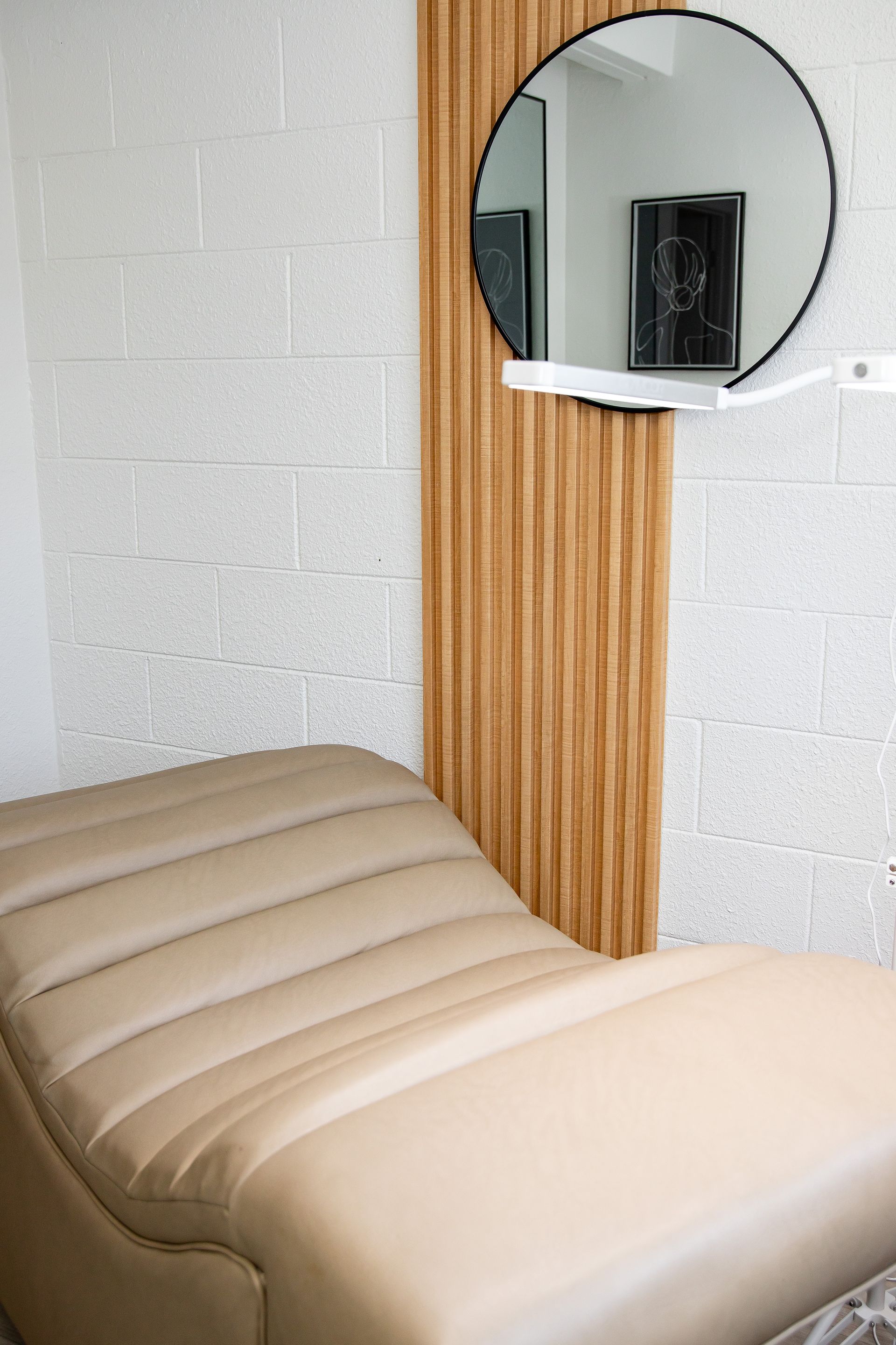 There is a round mirror on the wall next to a bed.