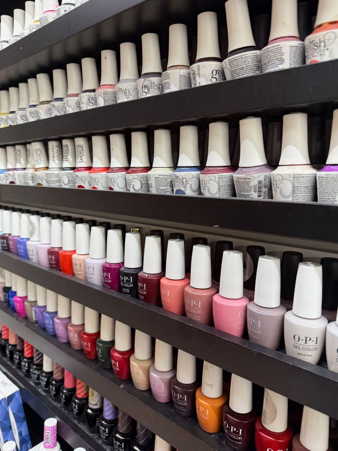 A woman is sitting at a table in a nail salon getting her nails done.