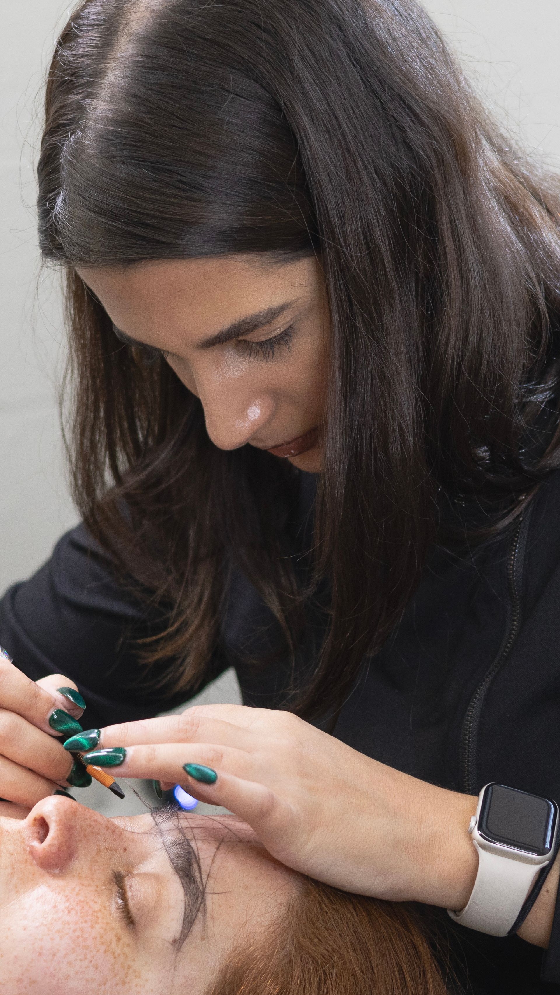 A woman is applying eyelash extensions to a woman 's eye.