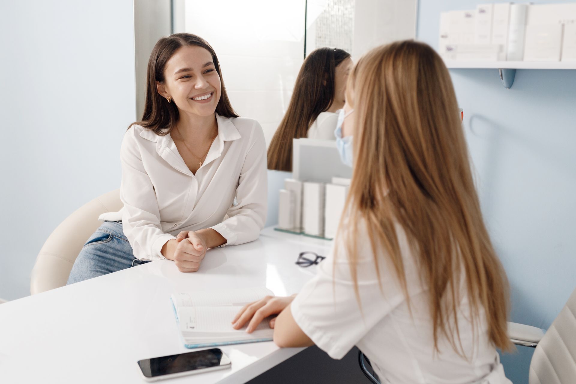 Two women are sitting at a table talking to each other.