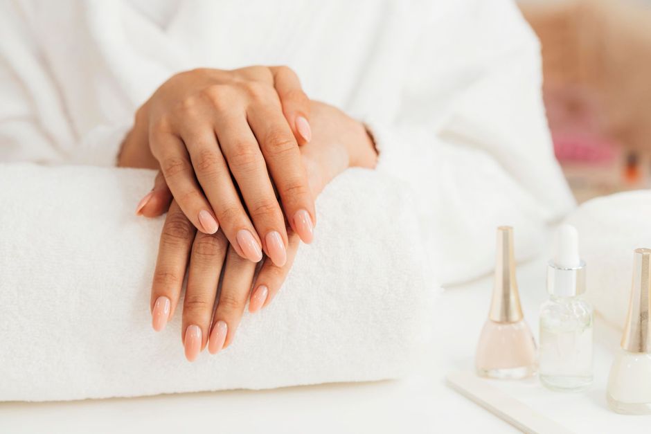 A woman is sitting on a towel with her hands on her nails.