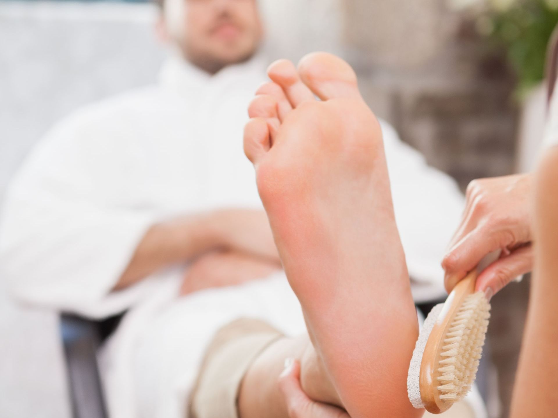 A woman is cleaning a man 's foot with a brush in a spa.