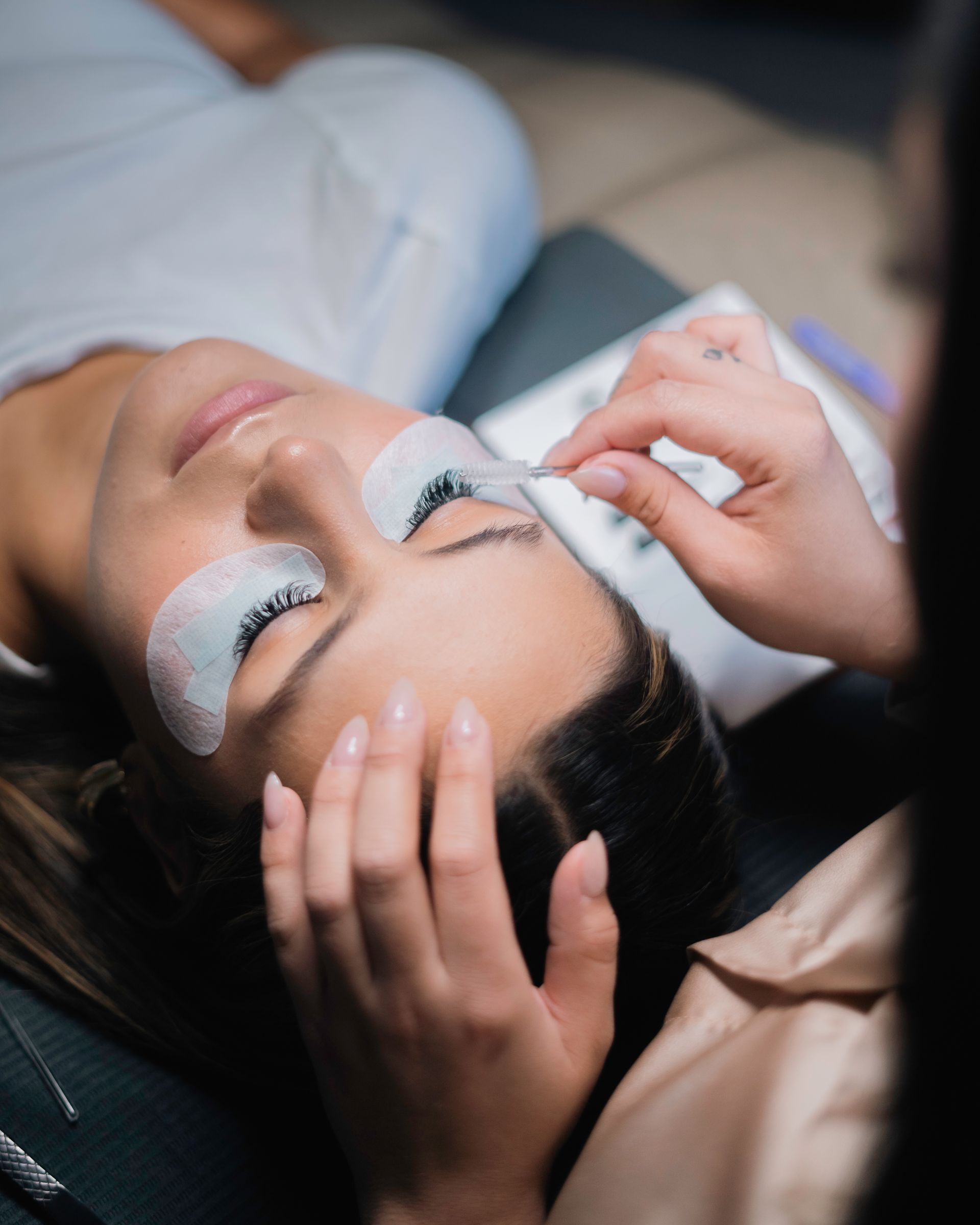 A woman is laying on a bed getting her eyelashes done