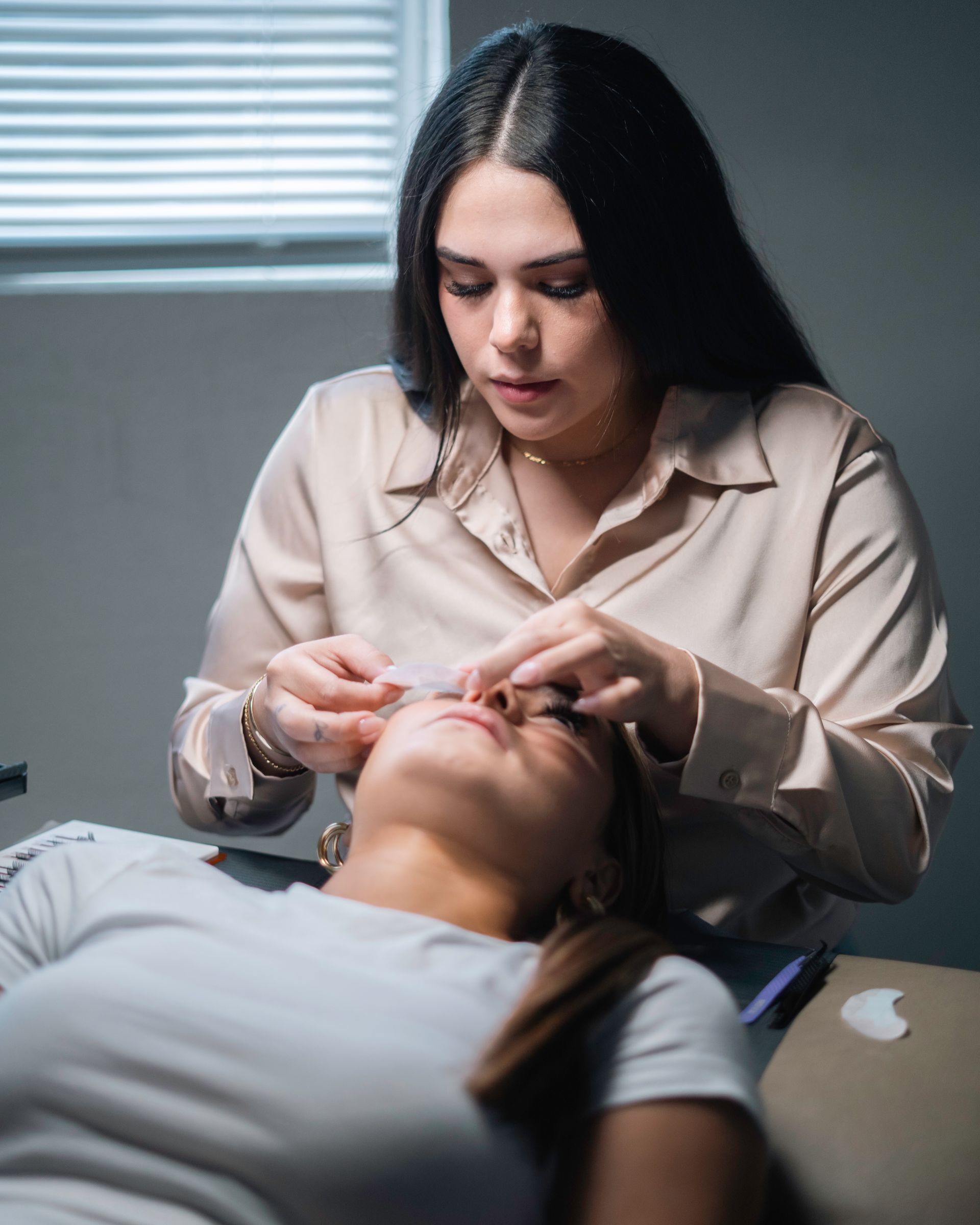 A woman is applying eyelash extensions to a woman 's eye.