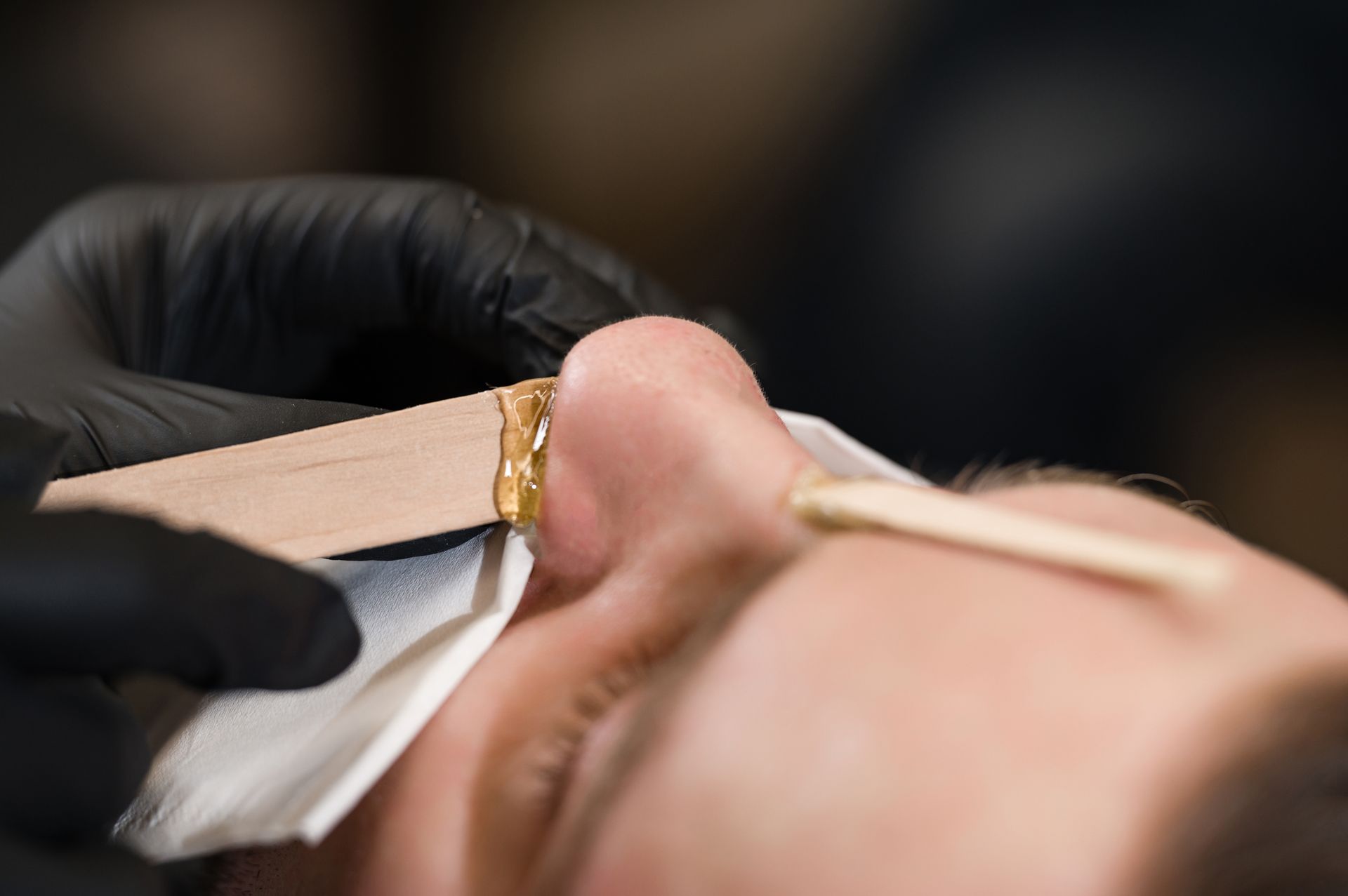 A close up of a person getting their nose waxed.