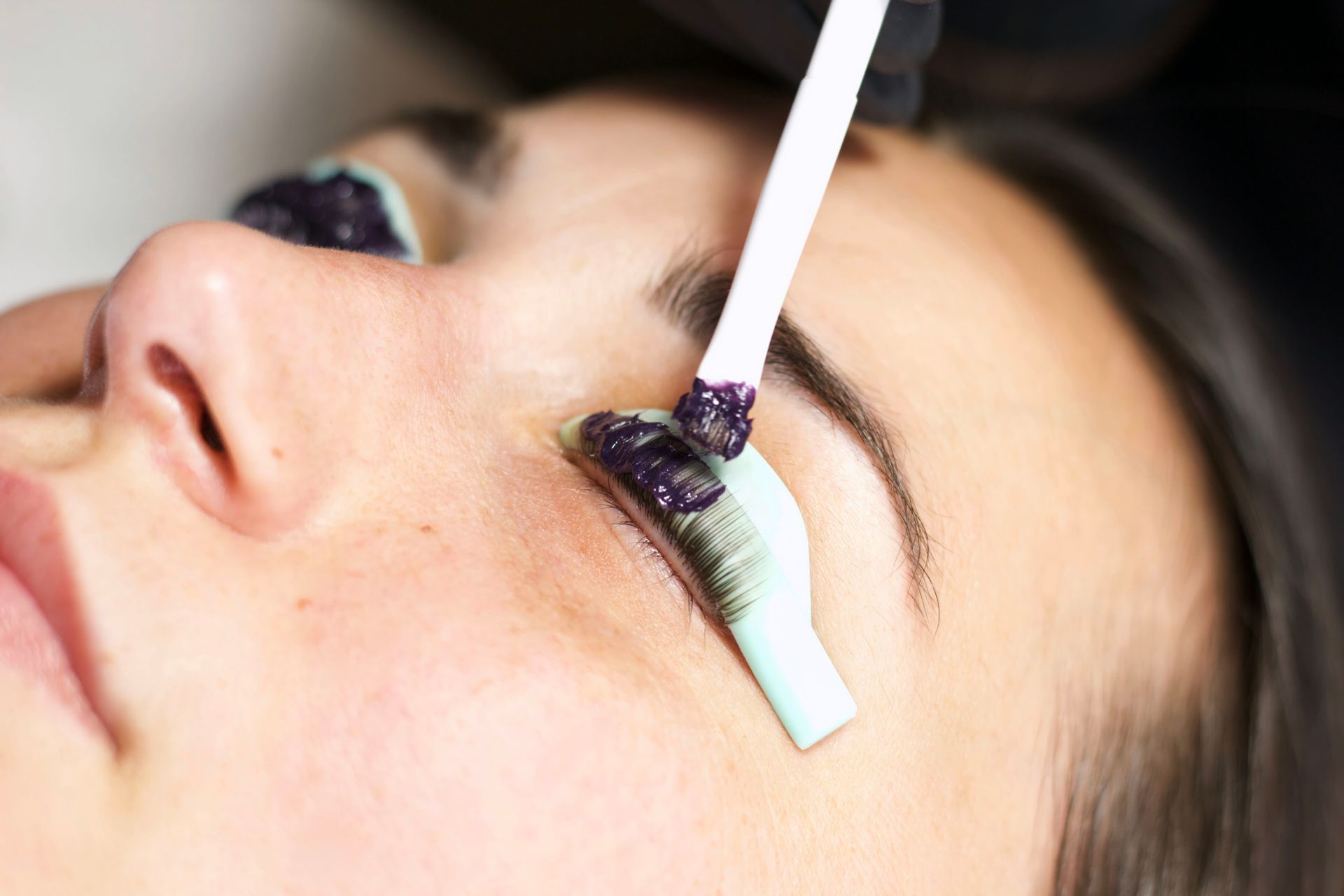 A woman is getting her eyelashes done at a beauty salon.