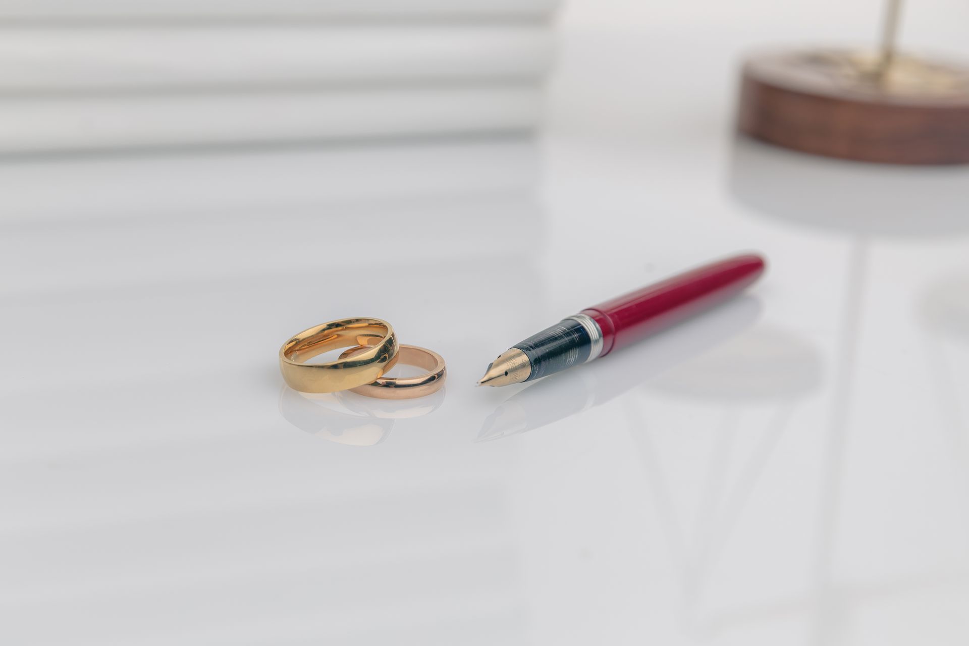 A pair of wedding rings and a pen are on a table.