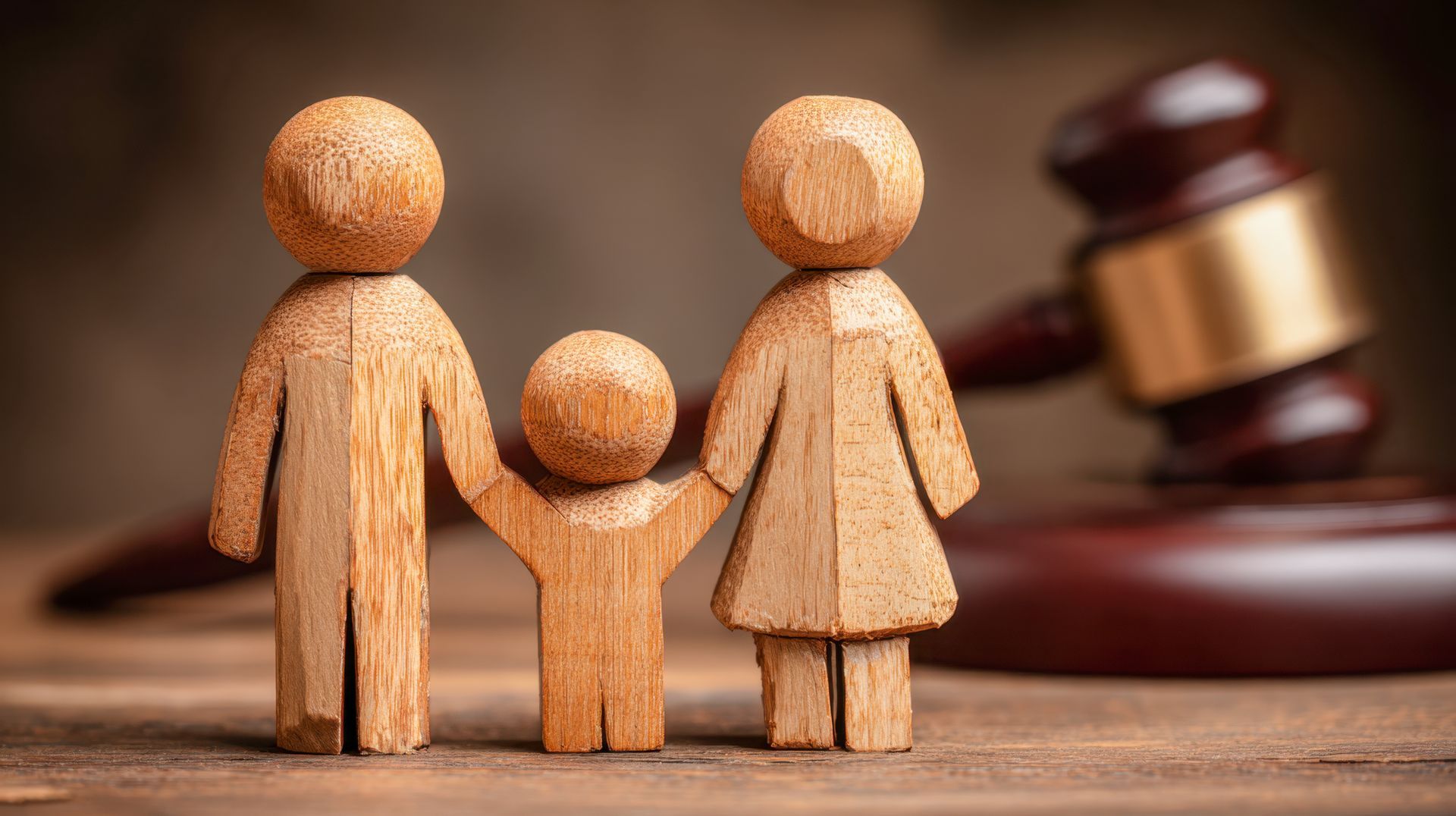 Wooden family figurines and gavel, symbolizing family law or legal proceedings.