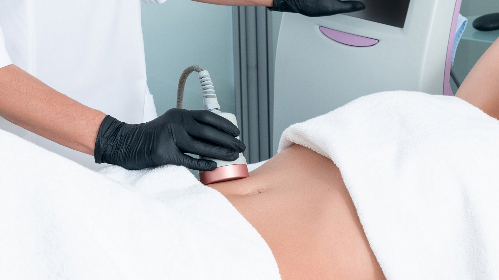 A woman is getting a cavitation treatment on her stomach.