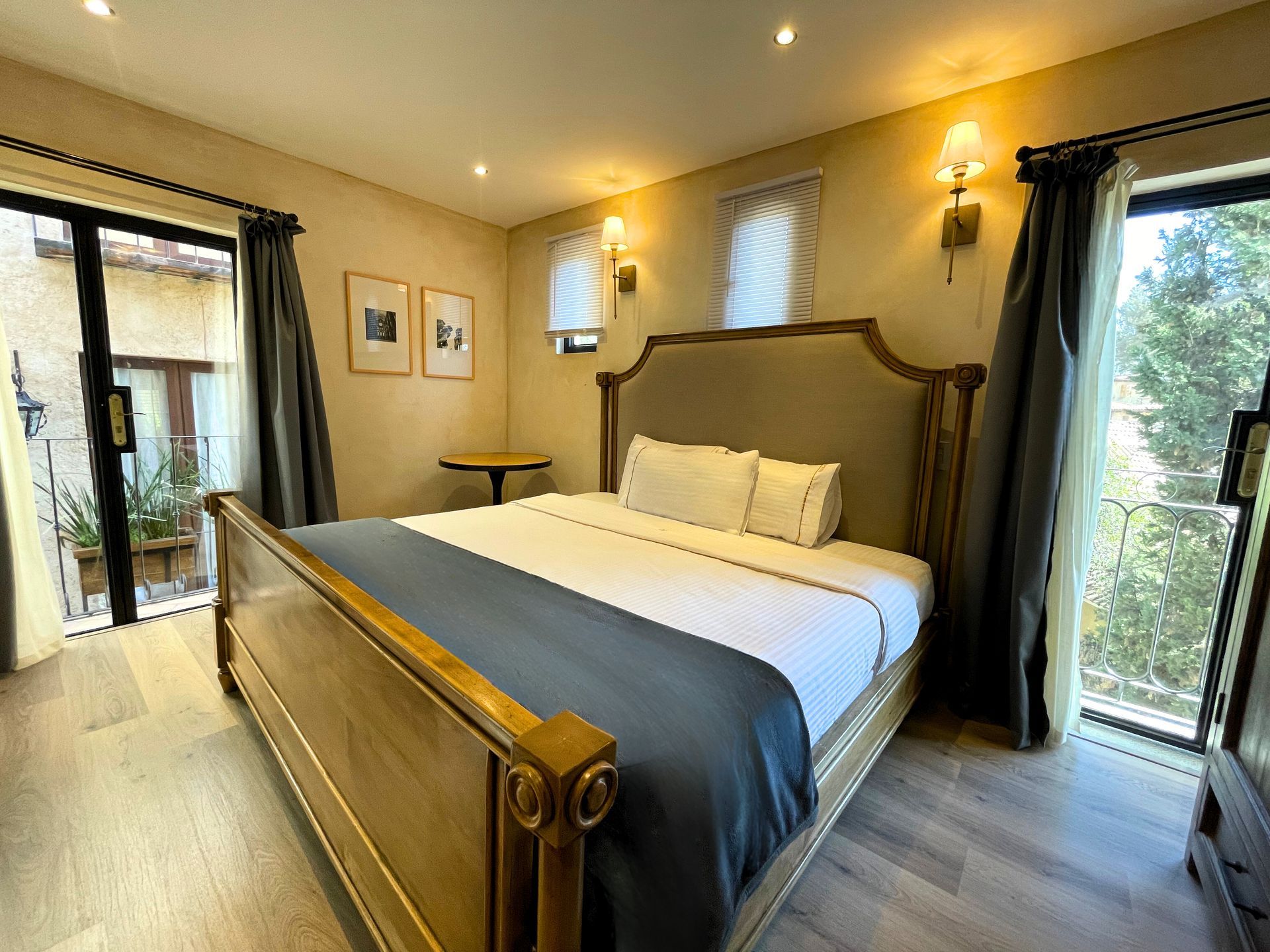 Cama con cabecero grande, tres almohadas blancas y dos apliques de pared.