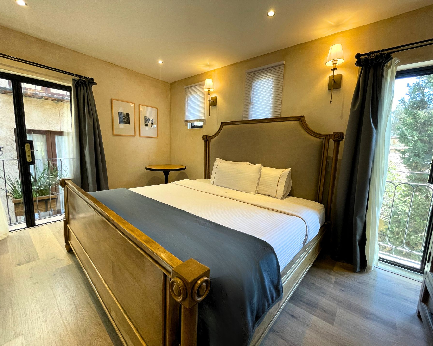 Cama con cabecero grande, tres almohadas blancas y dos apliques de pared.