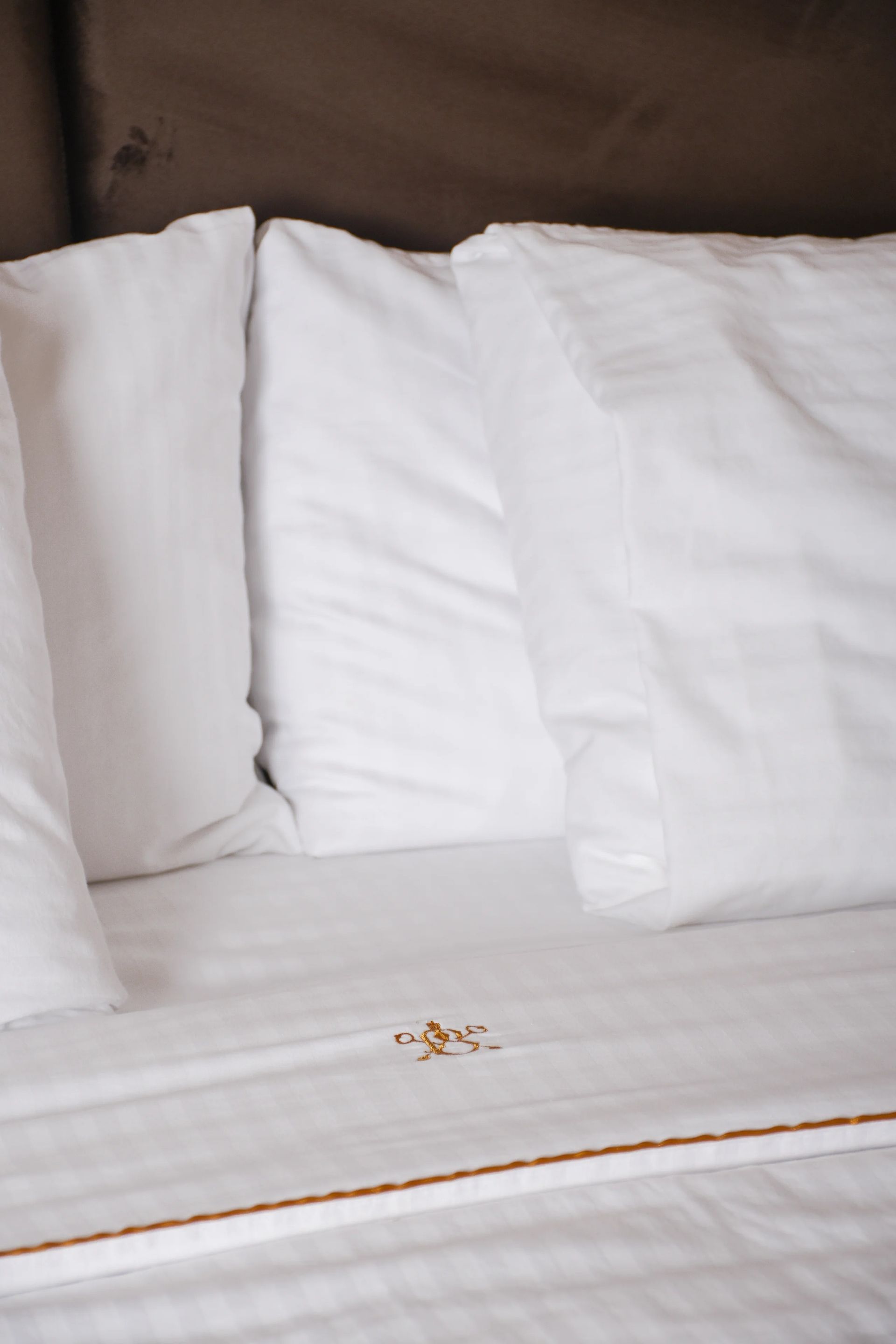 White pillows and bedding on a bed, with a small gold decorative element in the center.
