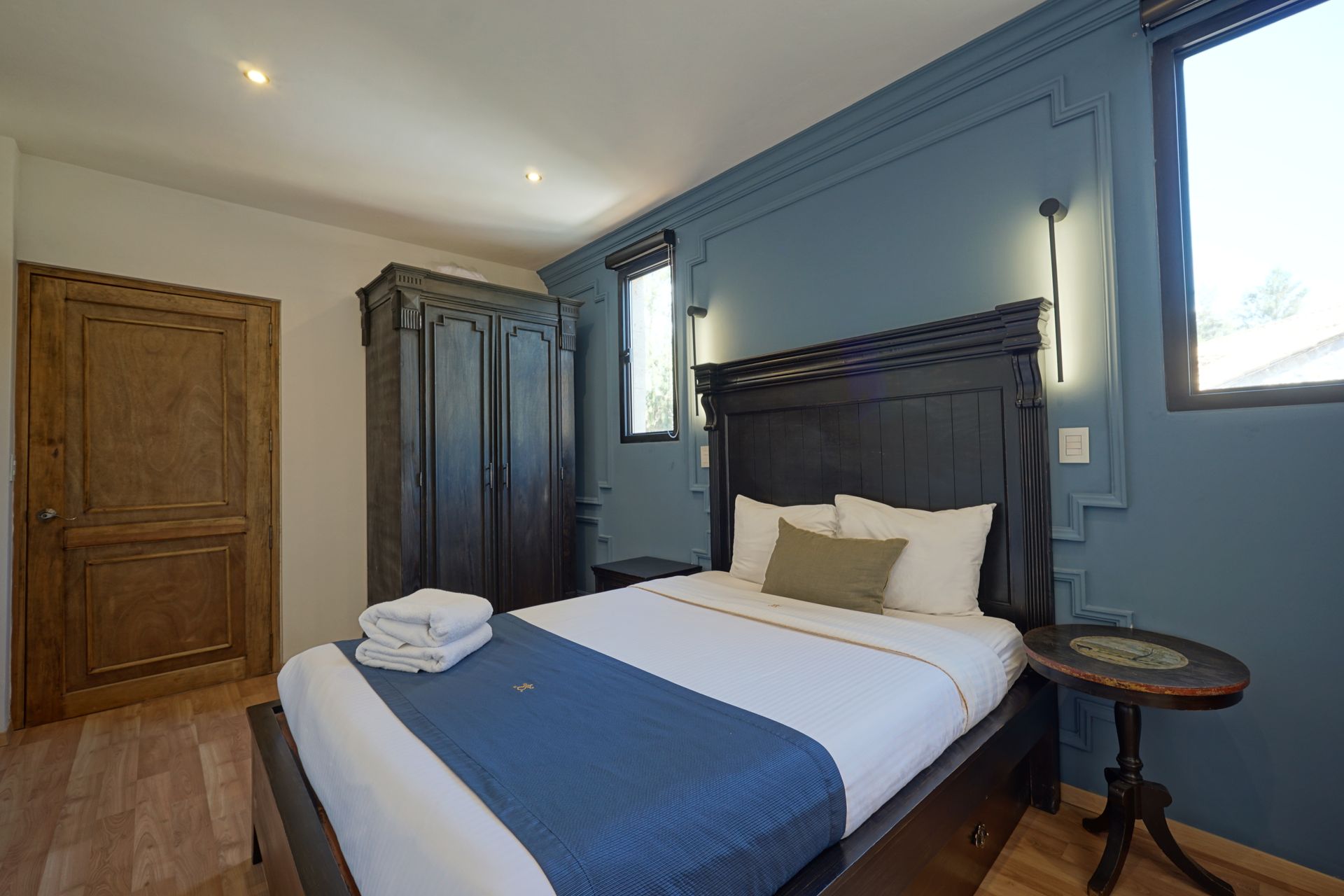 Sala de estar con pared de piedra, sofá con almohadones color crema, mesa de centro de madera y espejo.