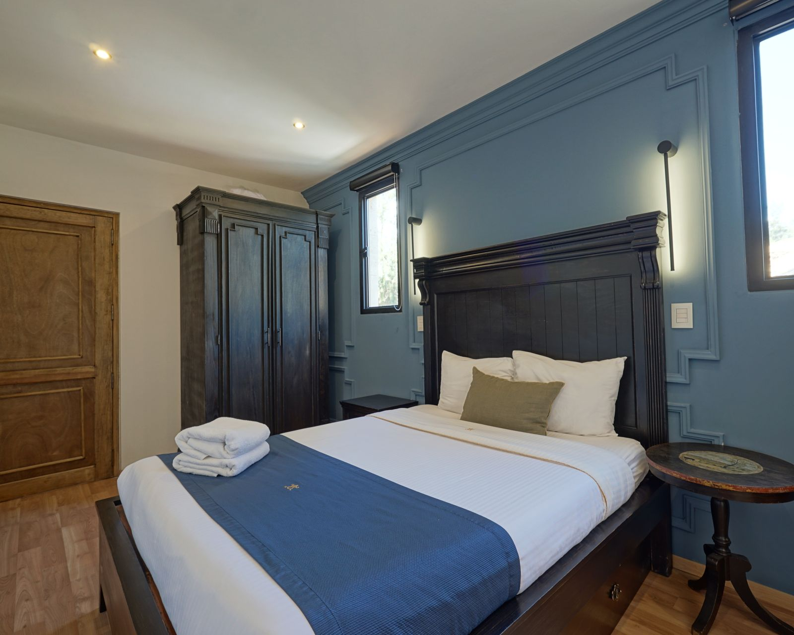 Sala de estar con pared de piedra, sofá con almohadones color crema, mesa de centro de madera y espejo.