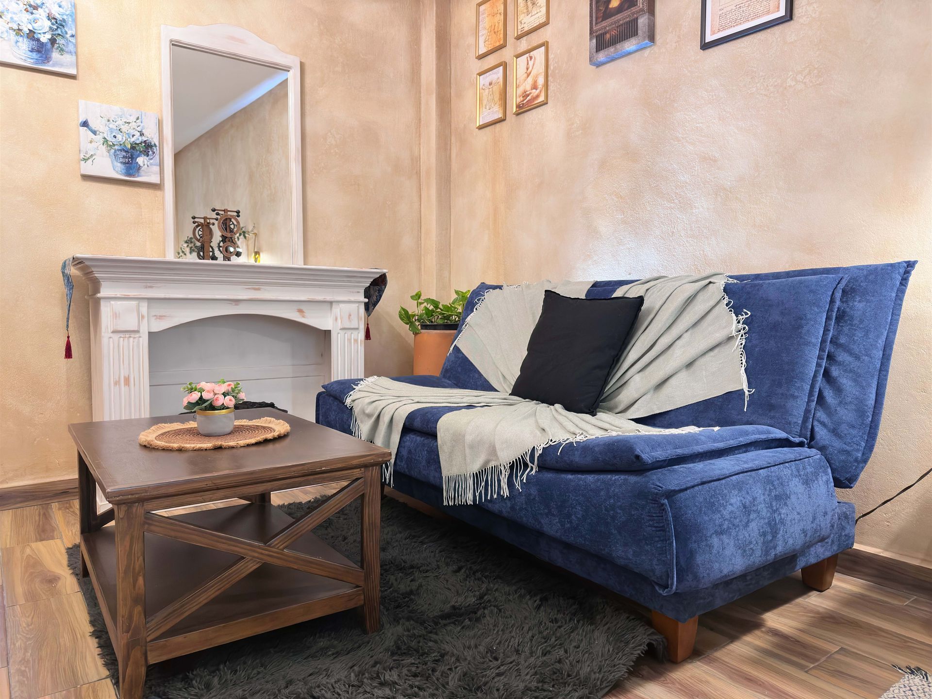 Cozy living room with blue sofa, wooden coffee table, white mantel, and framed wall art