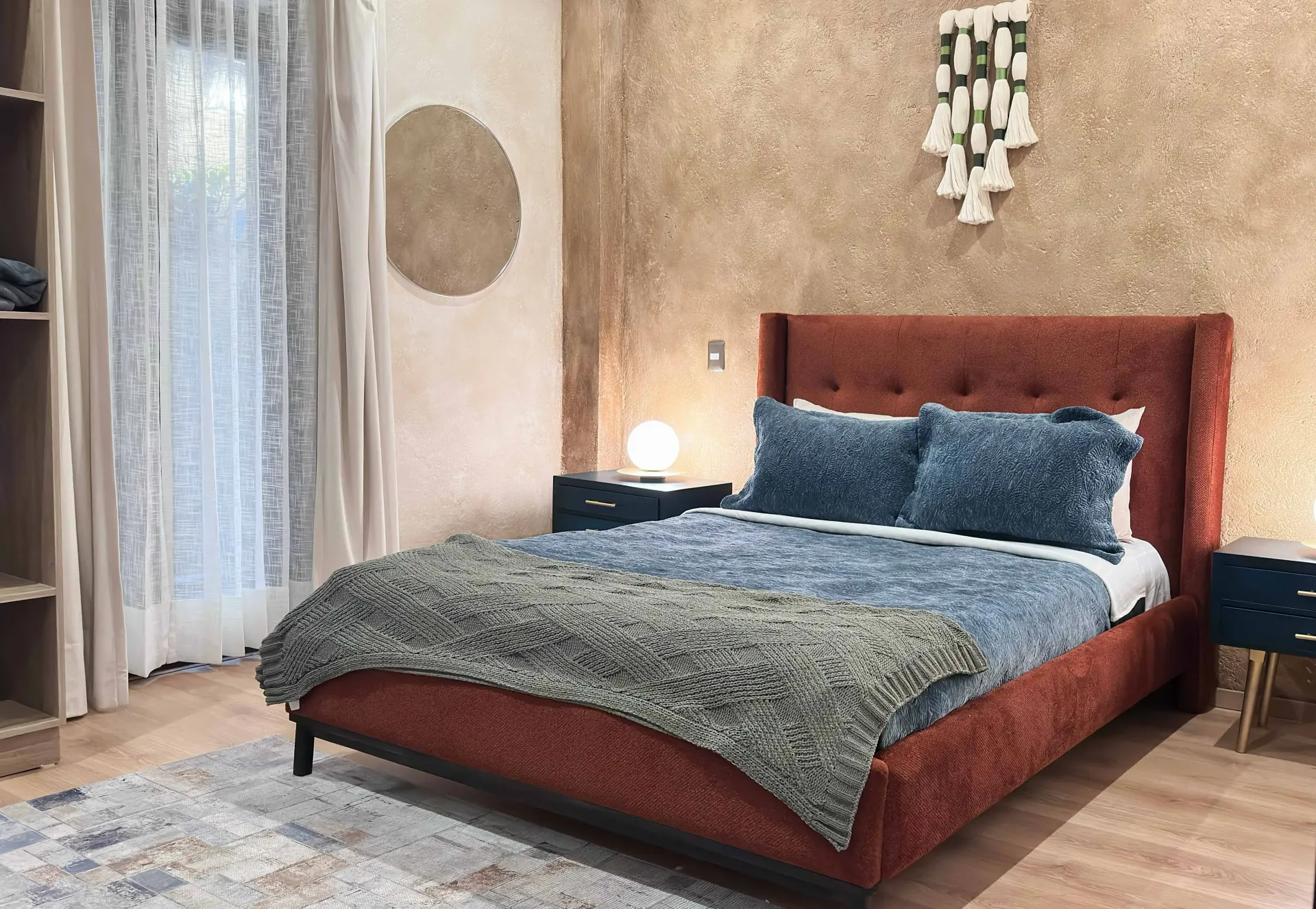 Cozy bedroom with a red bed, textured gold wall, and a patterned rug.