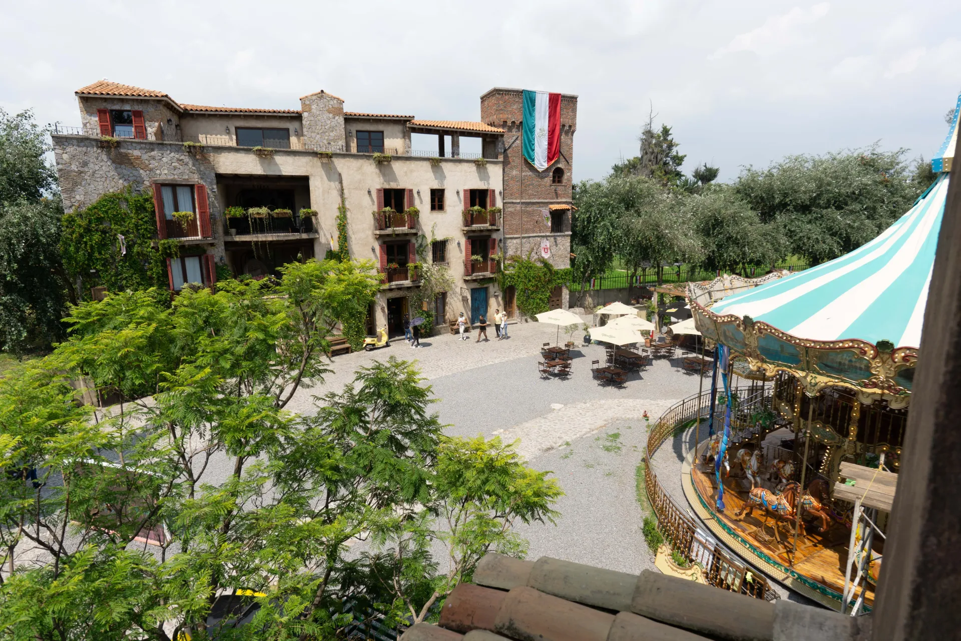 Stone castle with a carousel, outdoor seating, and trees.