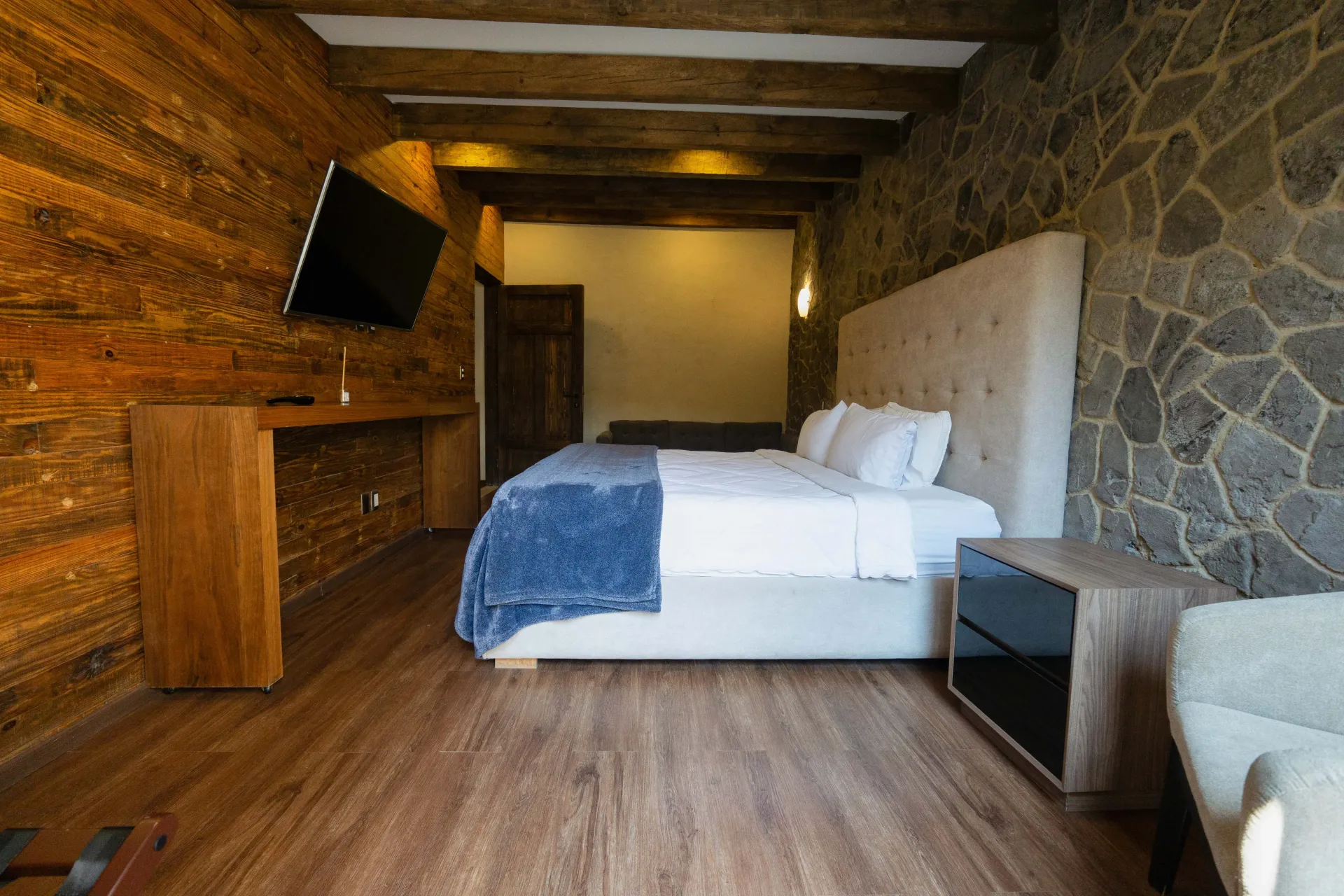 Hotel room with a bed, wooden walls, and stone accents.