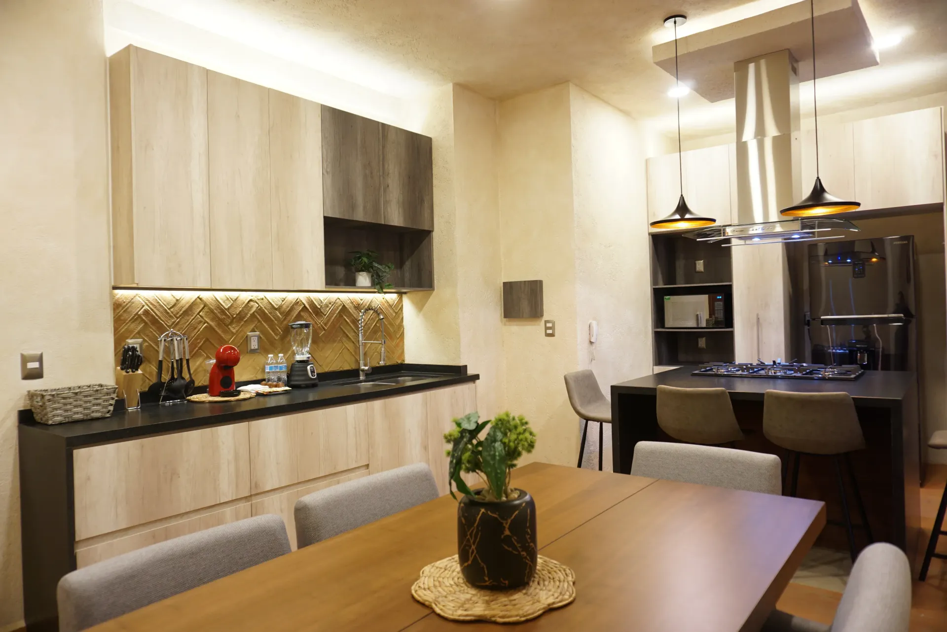Modern kitchen with wood cabinets, island with cooktop, and dining table.