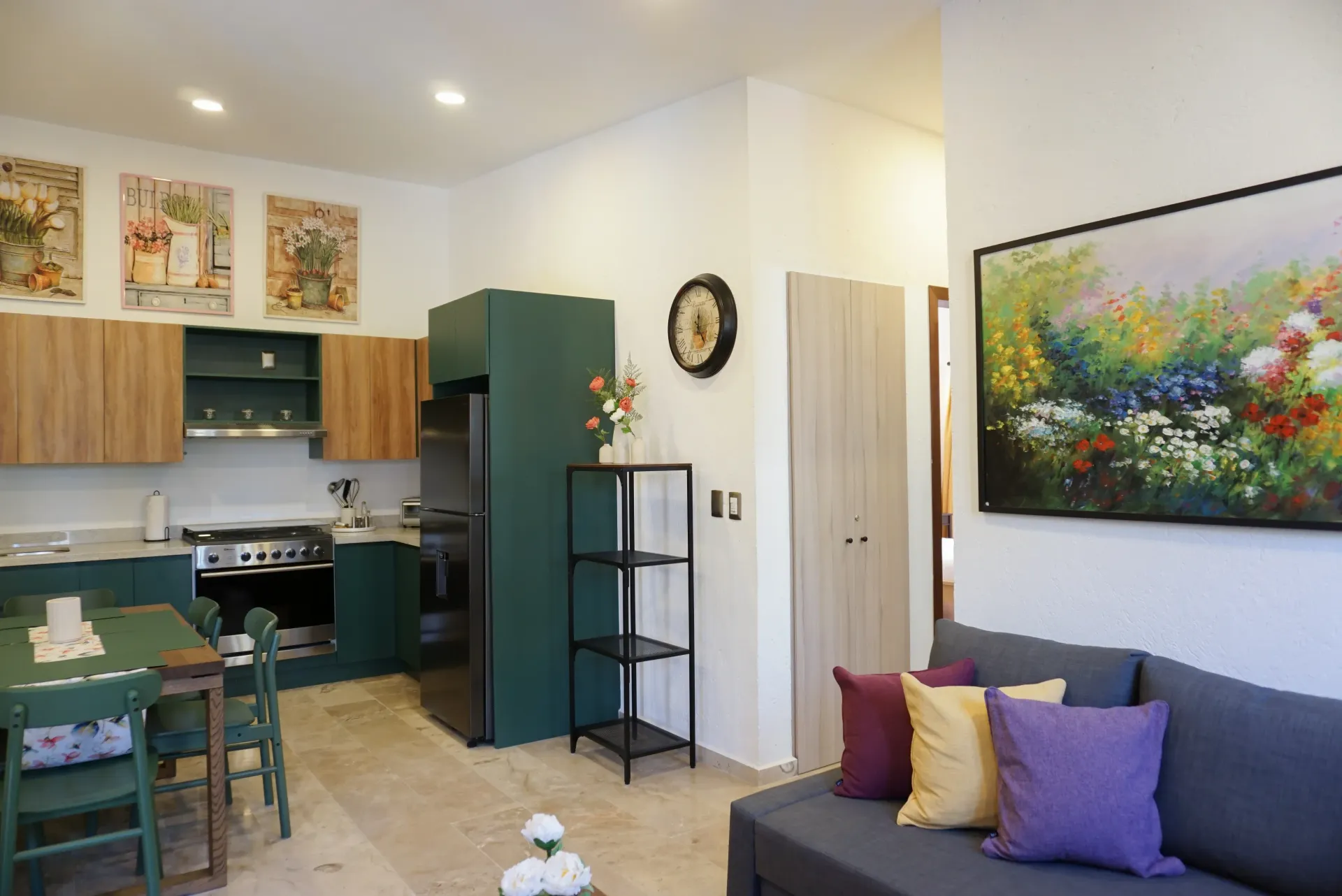 Cozy kitchen-living area with green cabinets, wooden cabinets, a green table and chairs, and a gray couch.