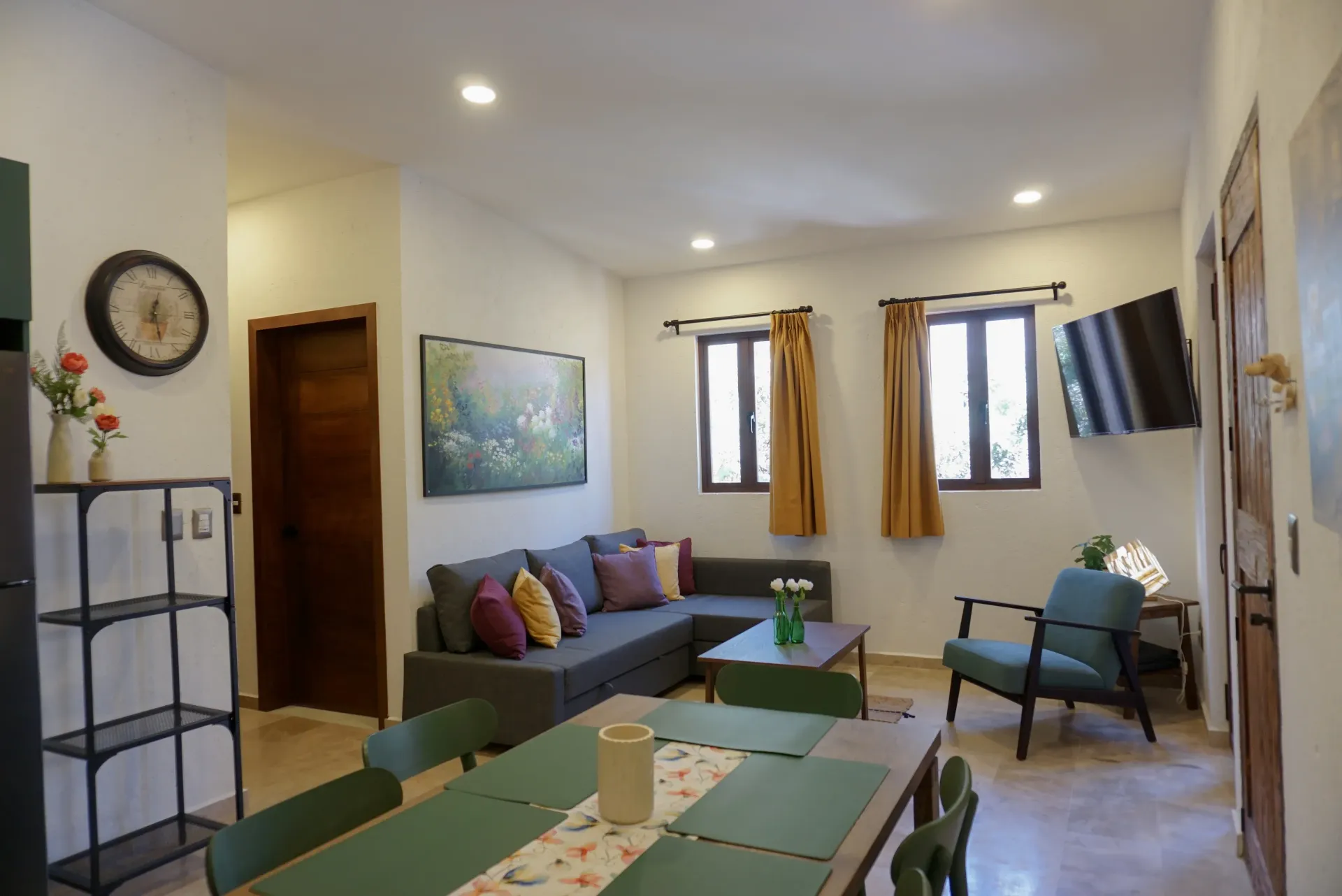 Living room with gray sectional, dining table, arm chair, TV, and decor.