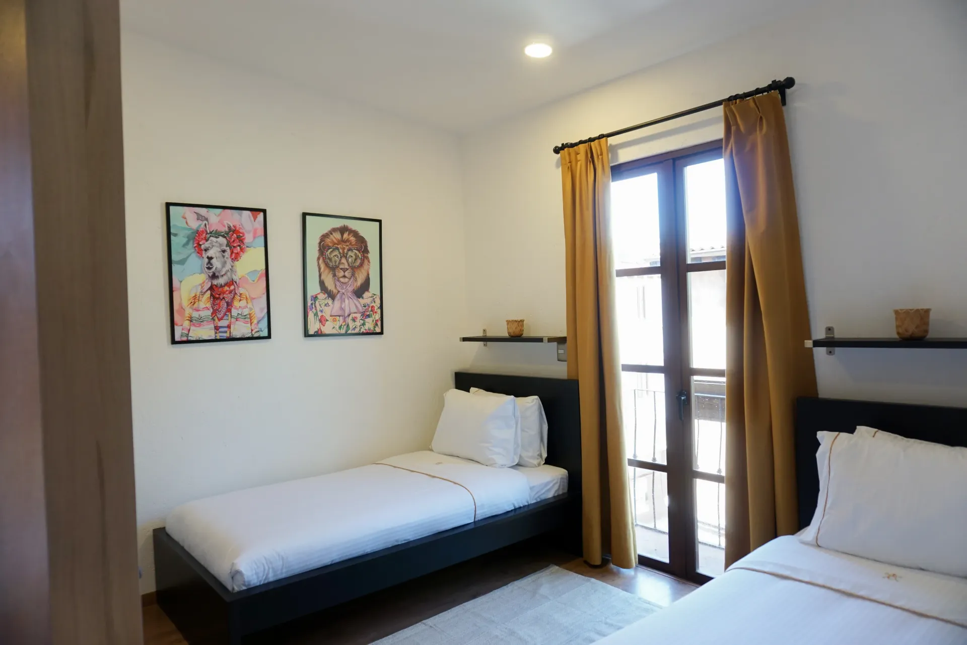 Two twin beds in a bright room with balcony access and colorful artwork on the wall.