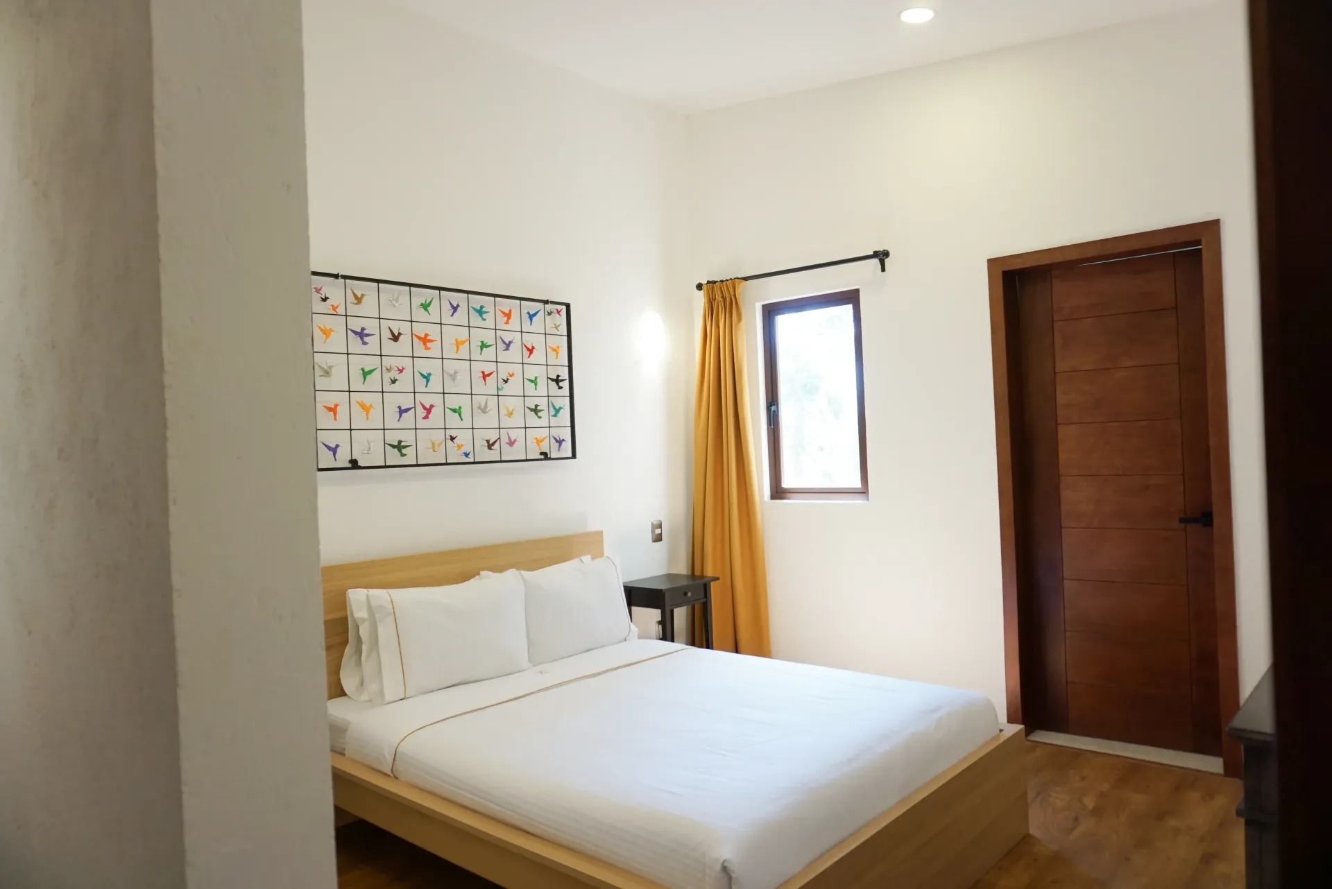Bedroom with white bedding, art, and a brown door.