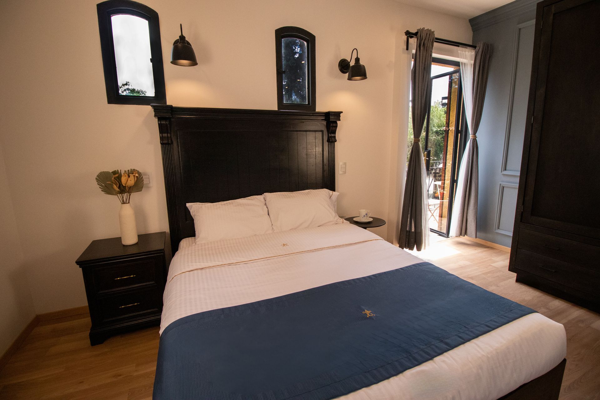 Bedroom with a black headboard, bed, nightstand, window, and door to a balcony.