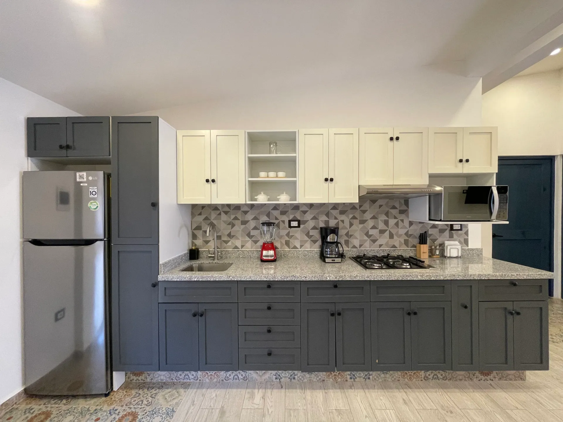 Kitchen with gray and cream cabinets, stainless steel appliances, and patterned backsplash.