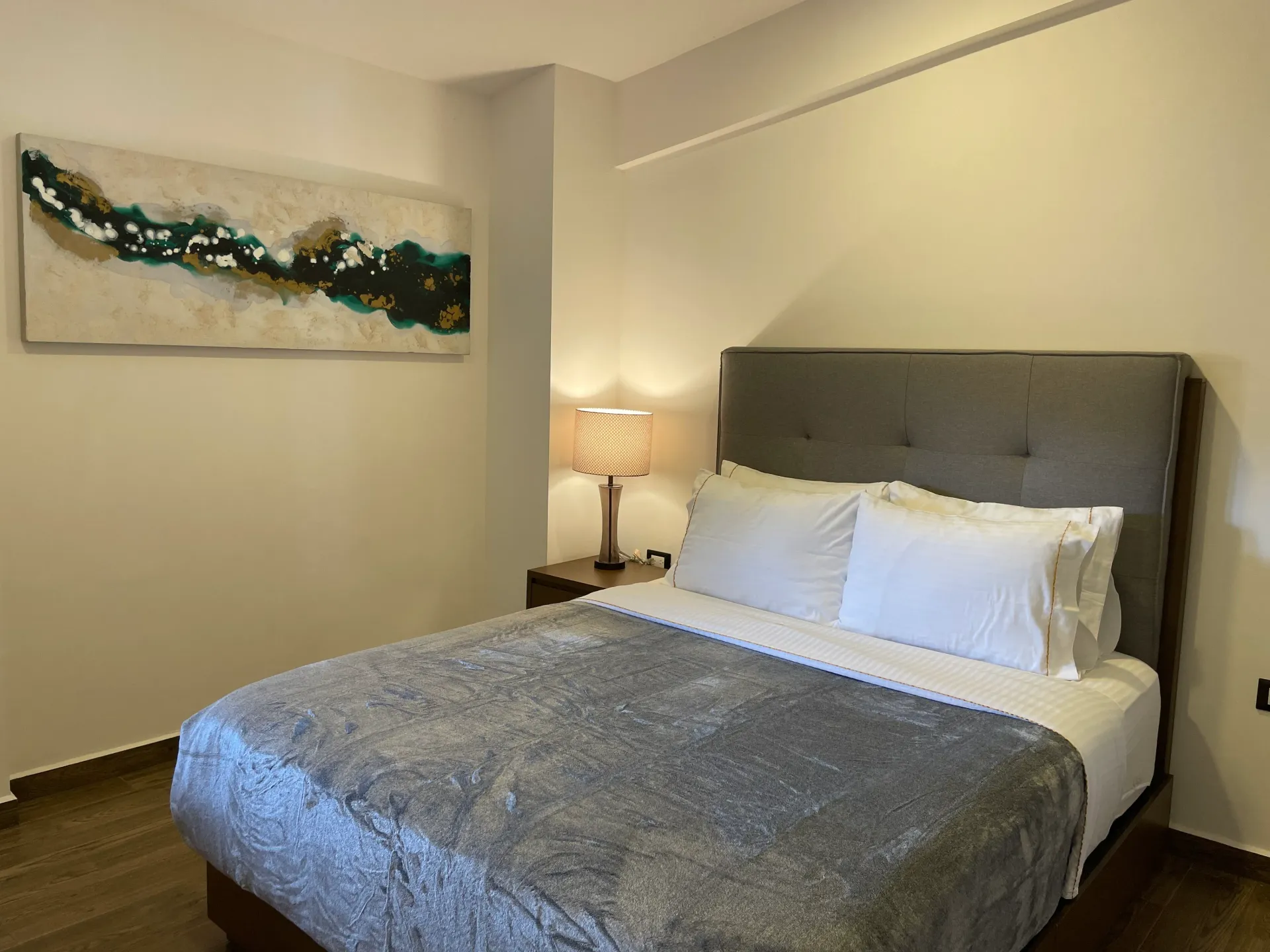 Bedroom with a gray bedspread, white pillows, and artwork on the wall.