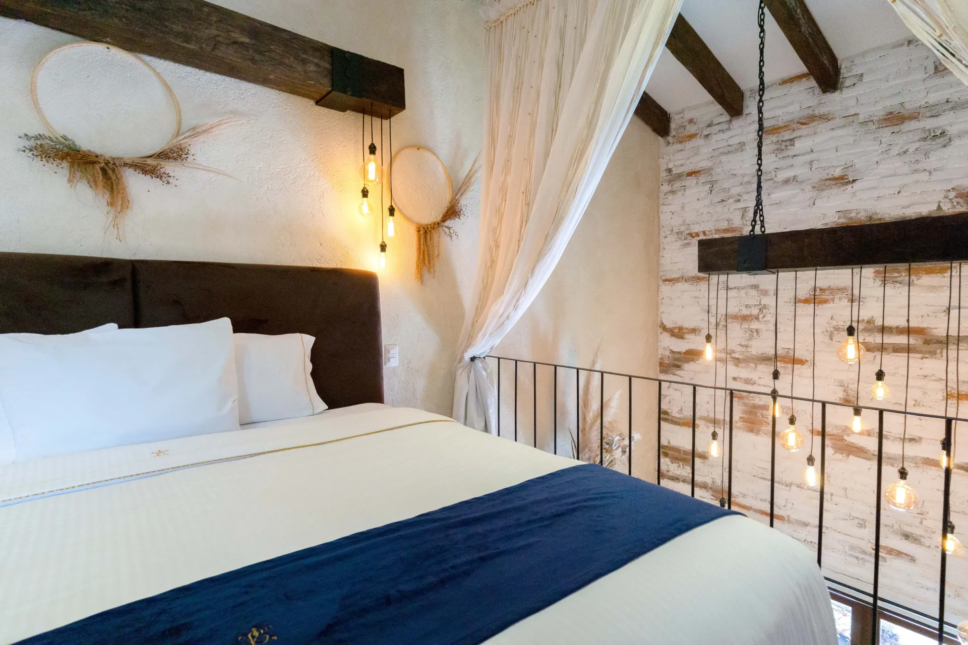 Bedroom with bed, exposed beams, string lights, and decorative hoops.