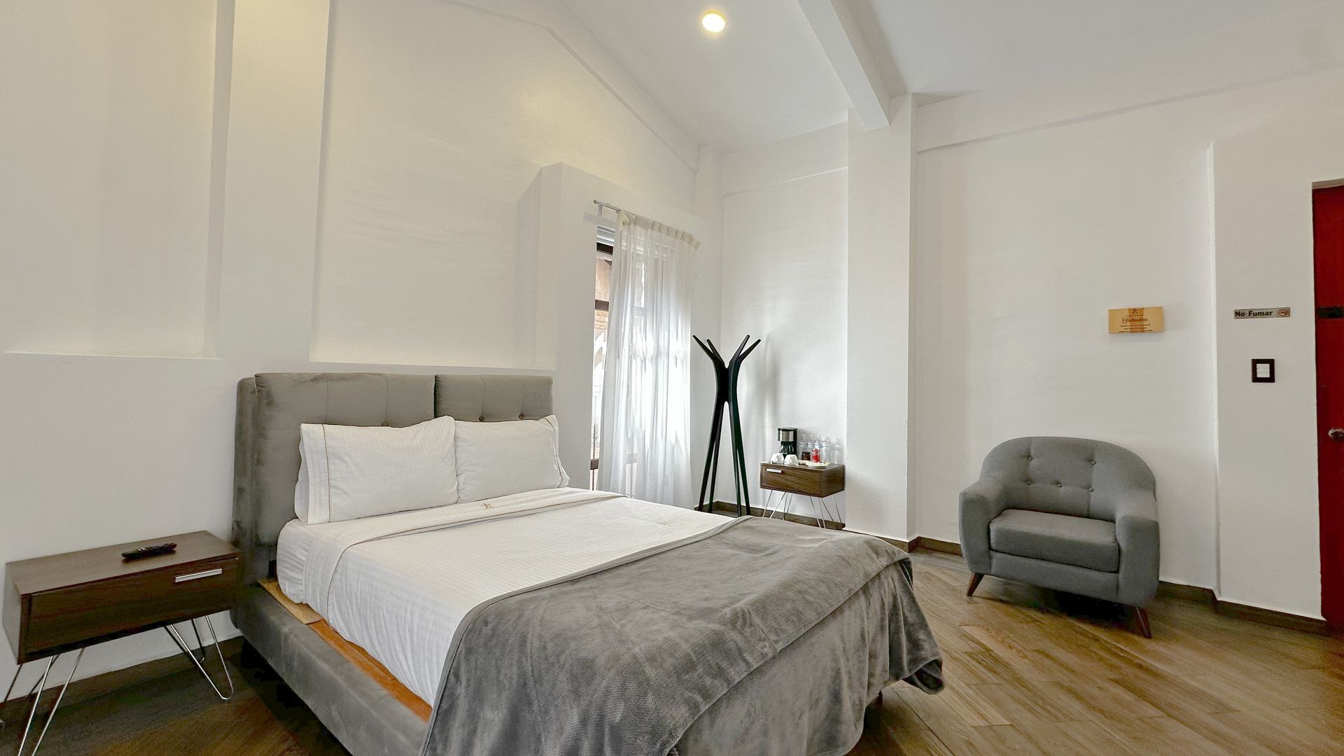 Dormitorio con cama, mesita de noche y puerta abierta a balcón.