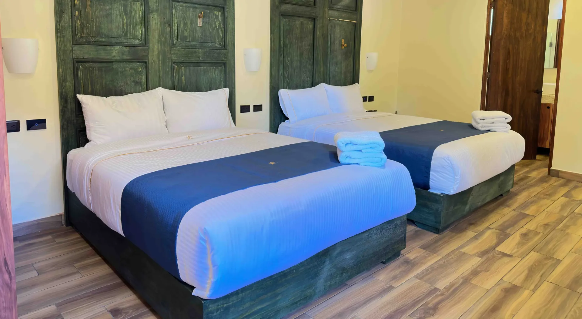 Two twin beds with white and blue bedding in a room with wooden accents.