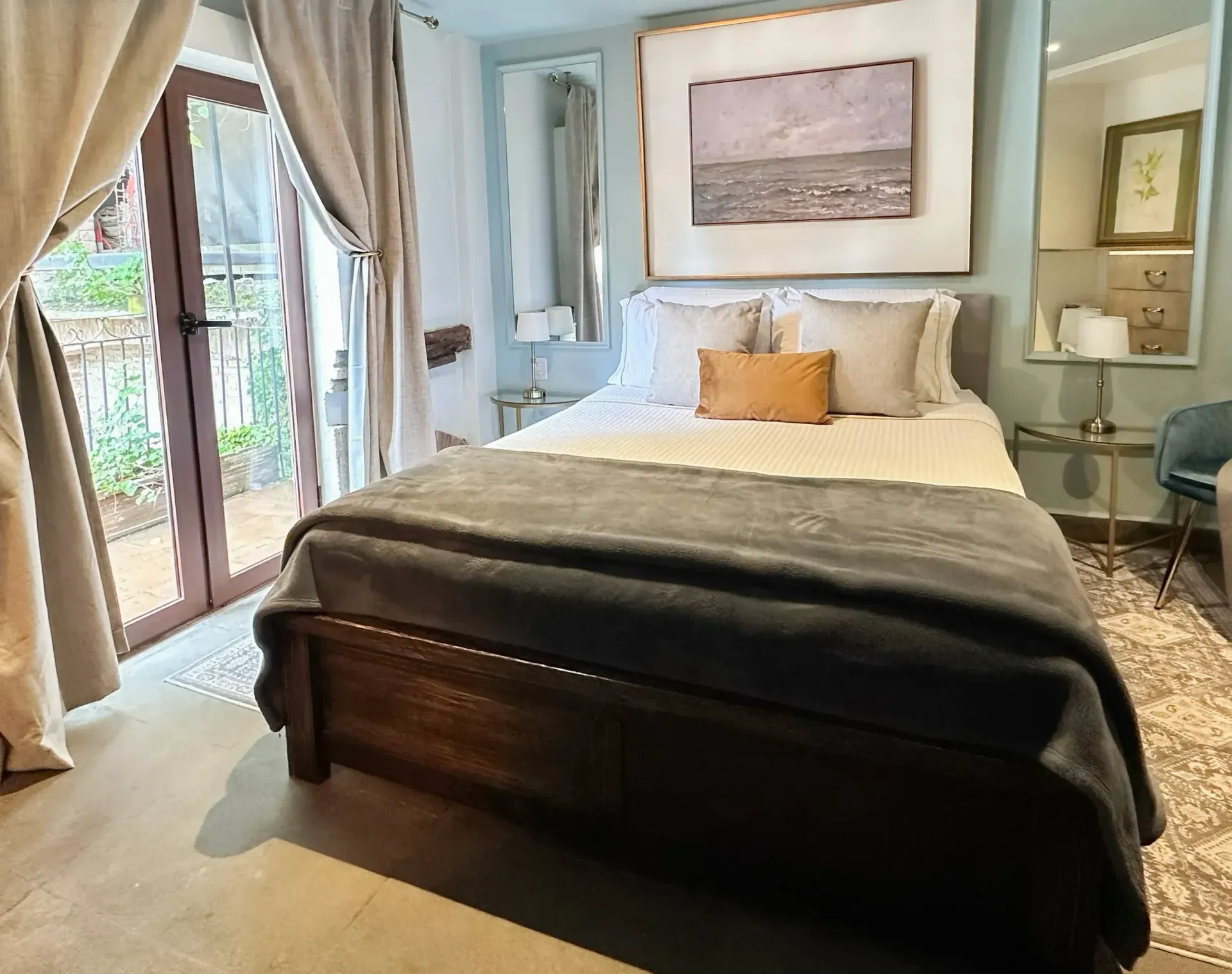 Bedroom with a wooden bed, balcony, painting, and decorative pillows.