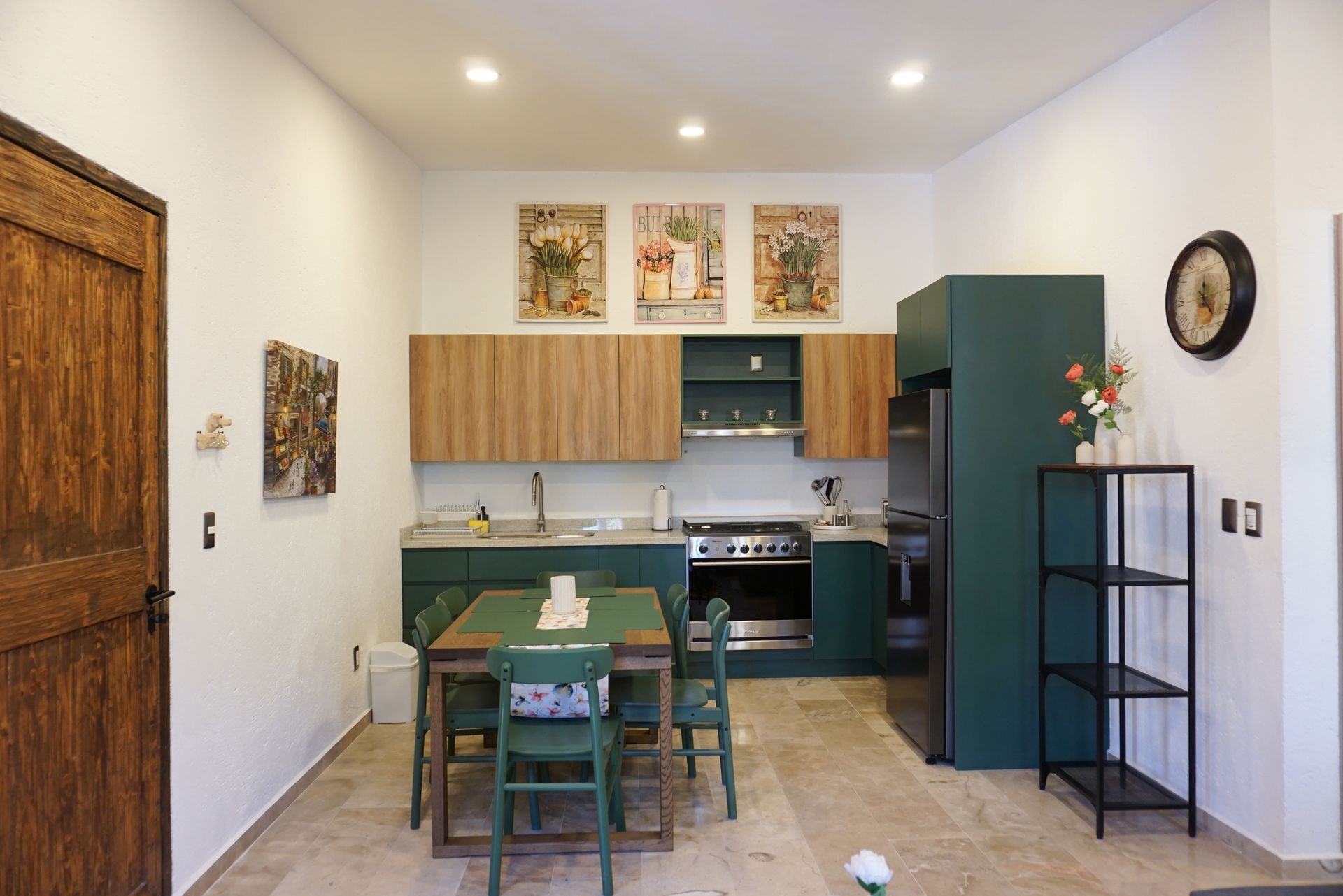 Small kitchen-dining area with green table, teal cabinets, and framed wall art.