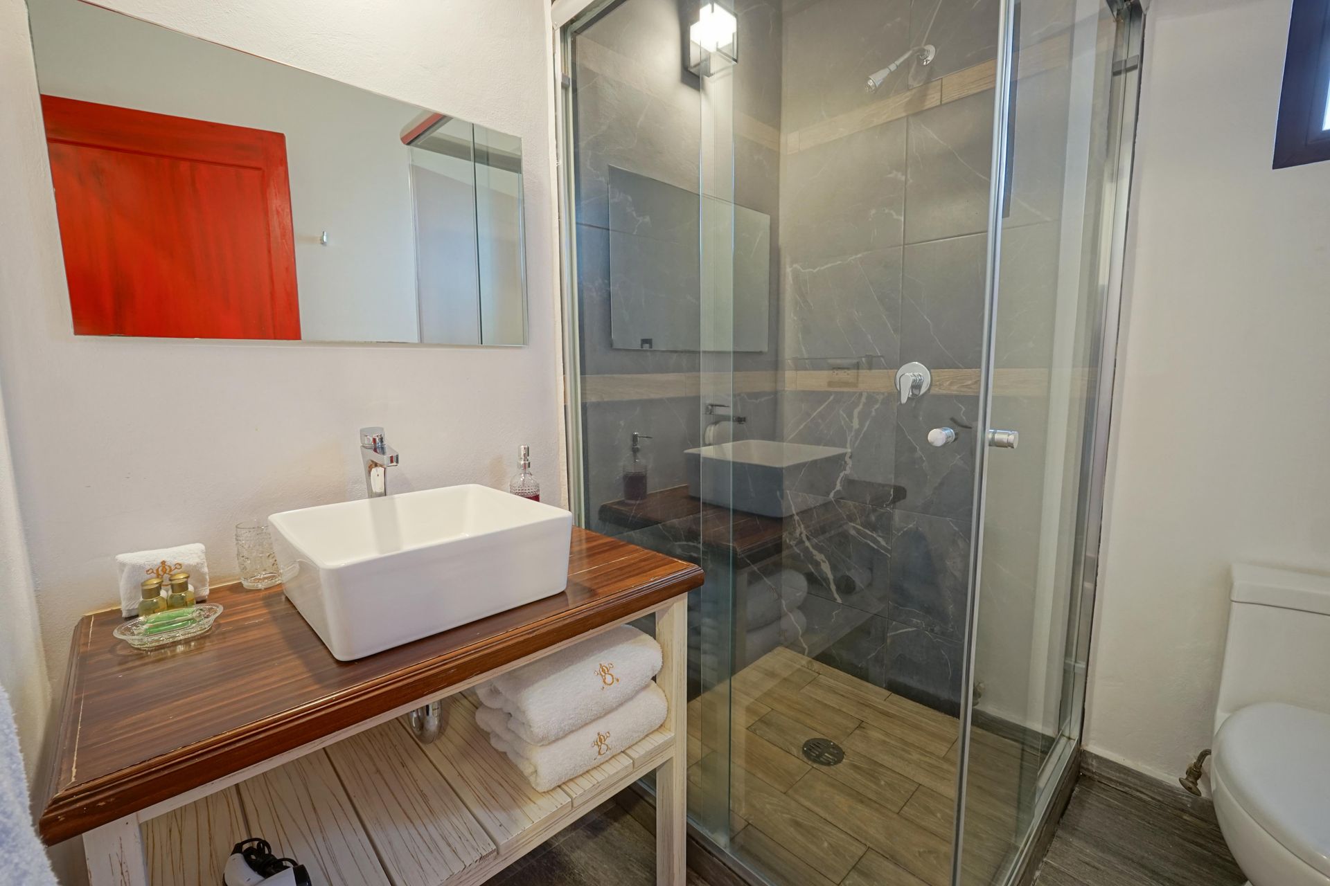 Modern bathroom with vessel sink, wood vanity, glass shower, and toilet